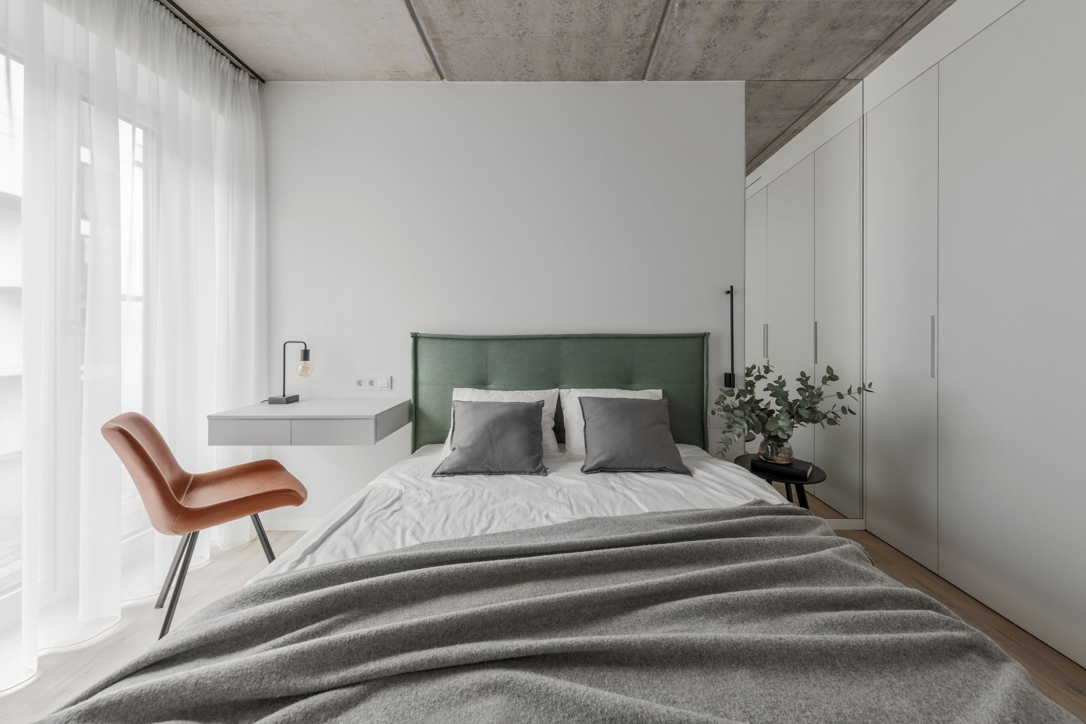 Dormitorio de matrimonio moderno con cabecero tapizado verde y decoración minimalista cálida