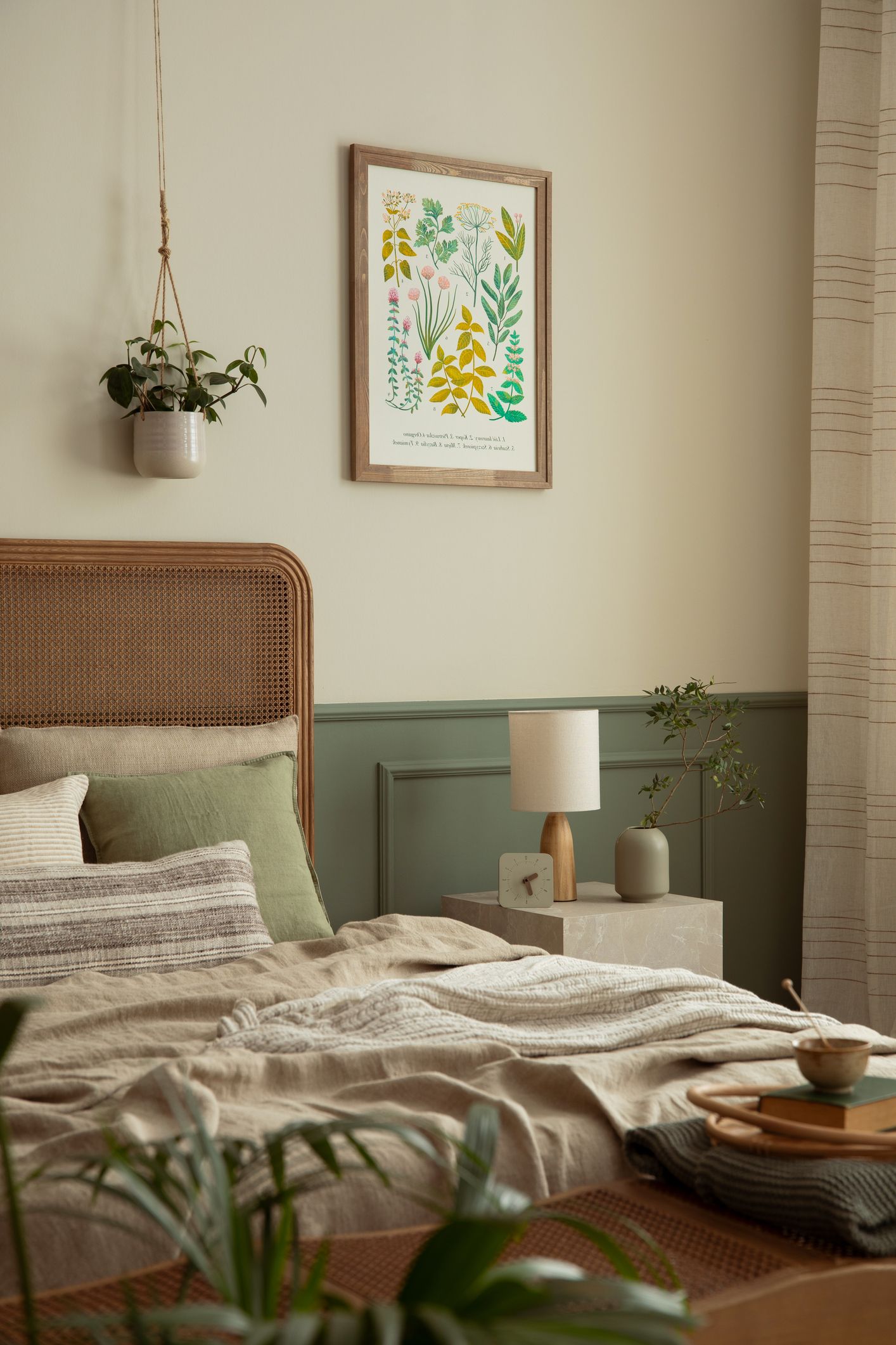 Dormitorio de matrimonio con detalles decorativos como lámina botánica, plantas y textiles naturales en tonos suaves