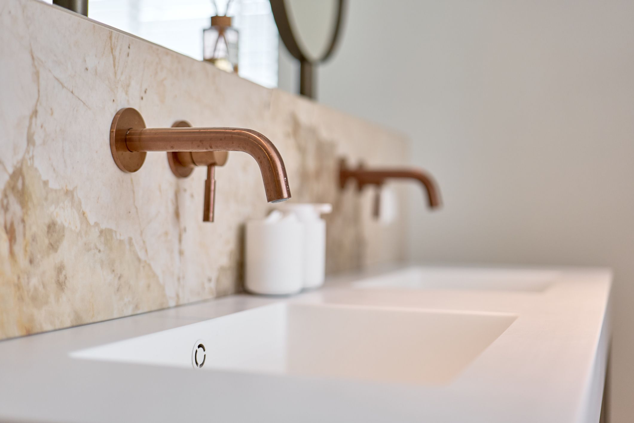 Grifería de baño en acabado latón envejecido sobre lavabo moderno con revestimiento de piedra
