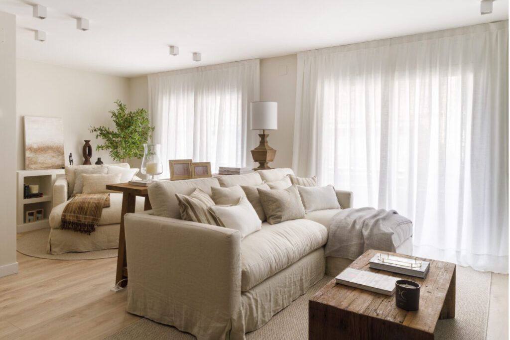 Salón con decoración aesthetic en tonos neutros, sofá beige, textiles naturales y luz natural abundante