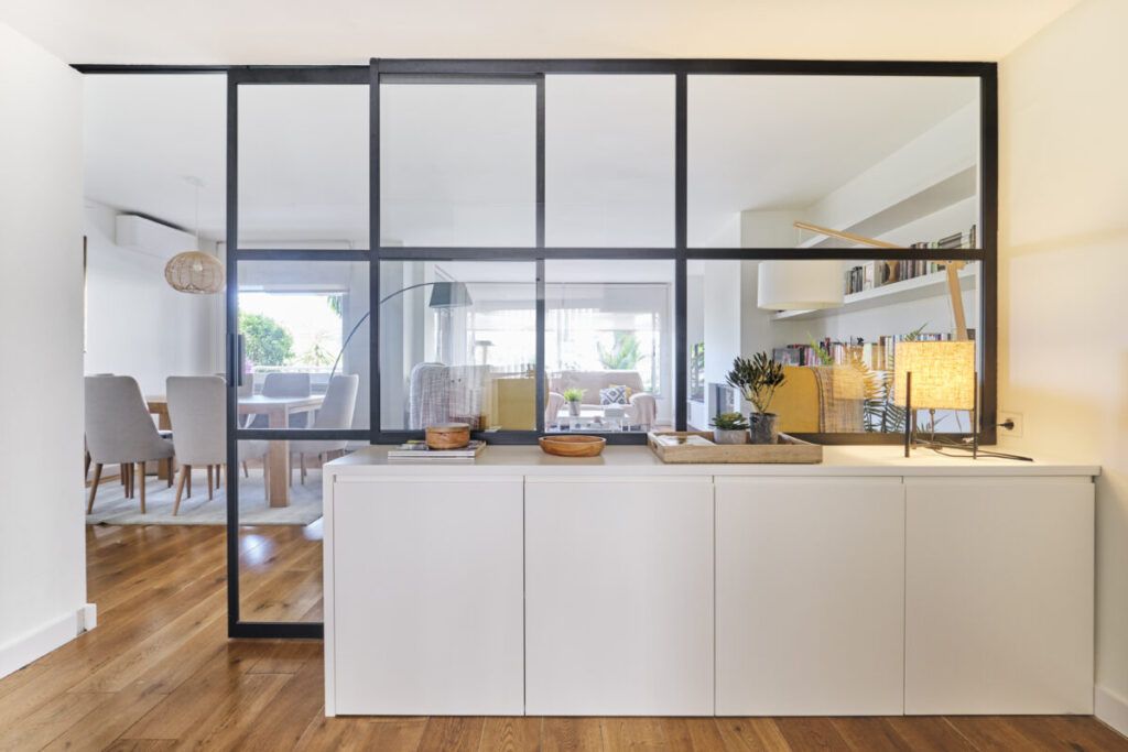 Cerramiento acristalado con perfilería negra que conecta salón y comedor y permite transformar el espacio sin reformar mejorando la luz y la distribución.