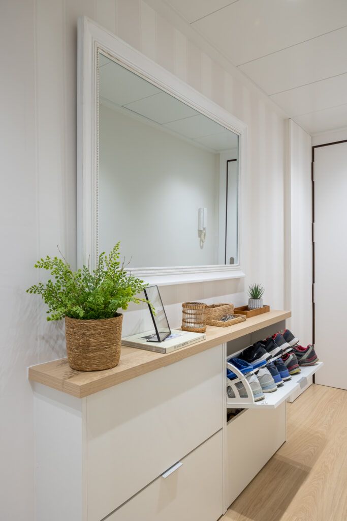 Recibidor con espejo de gran formato y mueble zapatero que muestra cómo transformar el espacio sin reformar mediante orden, almacenaje y efecto visual de amplitud.