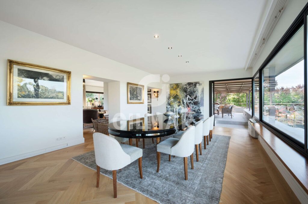 Comedor elegante con mesa para ocho personas y acceso a la terraza en chalet en Madrid situado en Ciudalcampo.