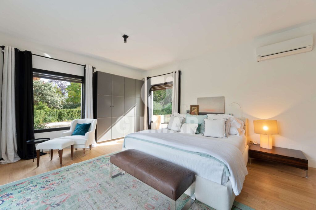 Dormitorio principal con grandes ventanales y vistas al jardín en chalet en Madrid situado en Ciudalcampo.