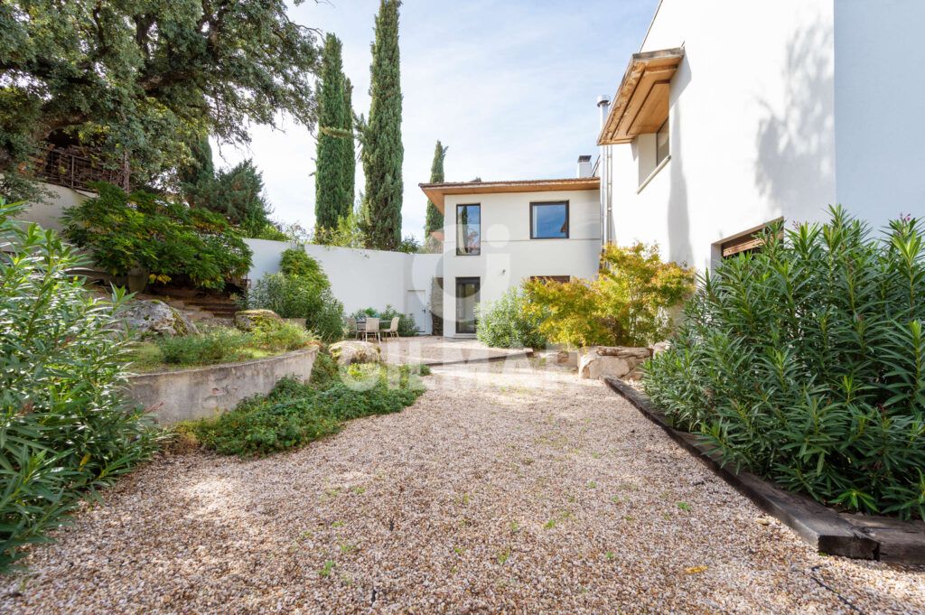 Jardín con camino de grava y vegetación en un chalet en Madrid situado en Ciudalcampo.