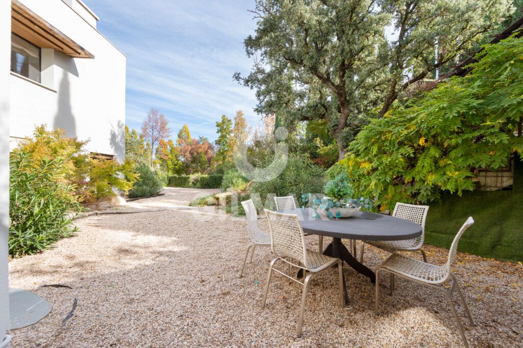 Comedor exterior en el jardín de un chalet en Ciudalcampo Madrid rodeado de árboles.