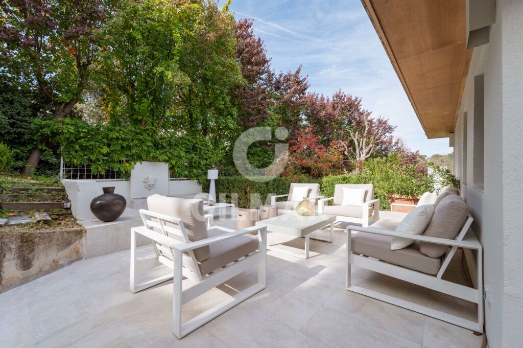 Terraza de jardín en chalet en Madrid con mobiliario exterior y vegetación.
