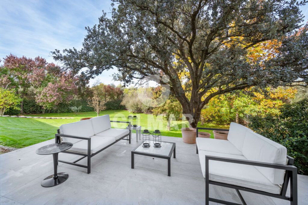 Terraza de jardín en chalet en Madrid con mobiliario exterior y vegetación.