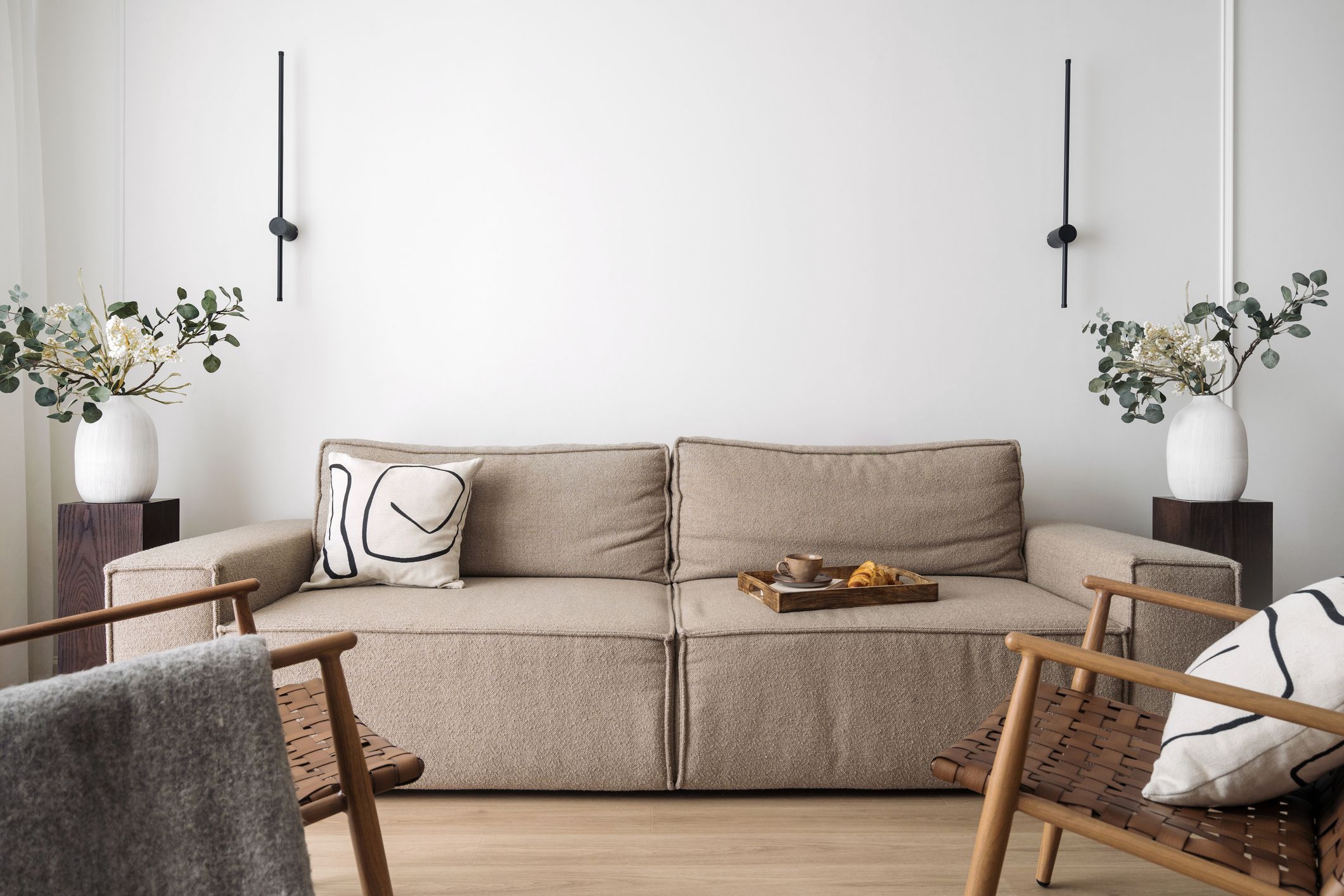Salón pequeño con sofá beige y apliques negros en la pared, idea sobre cómo decorar las paredes del salón ahorrando espacio