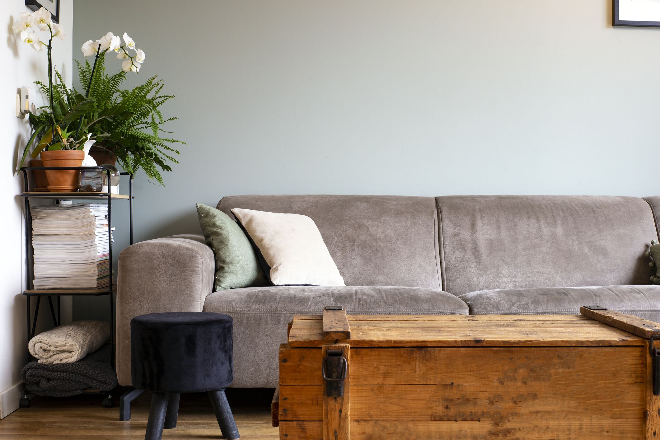 Baúl vintage usado como mesa auxiliar en el salón delante del sofá con almacenaje oculto y decoración moderna