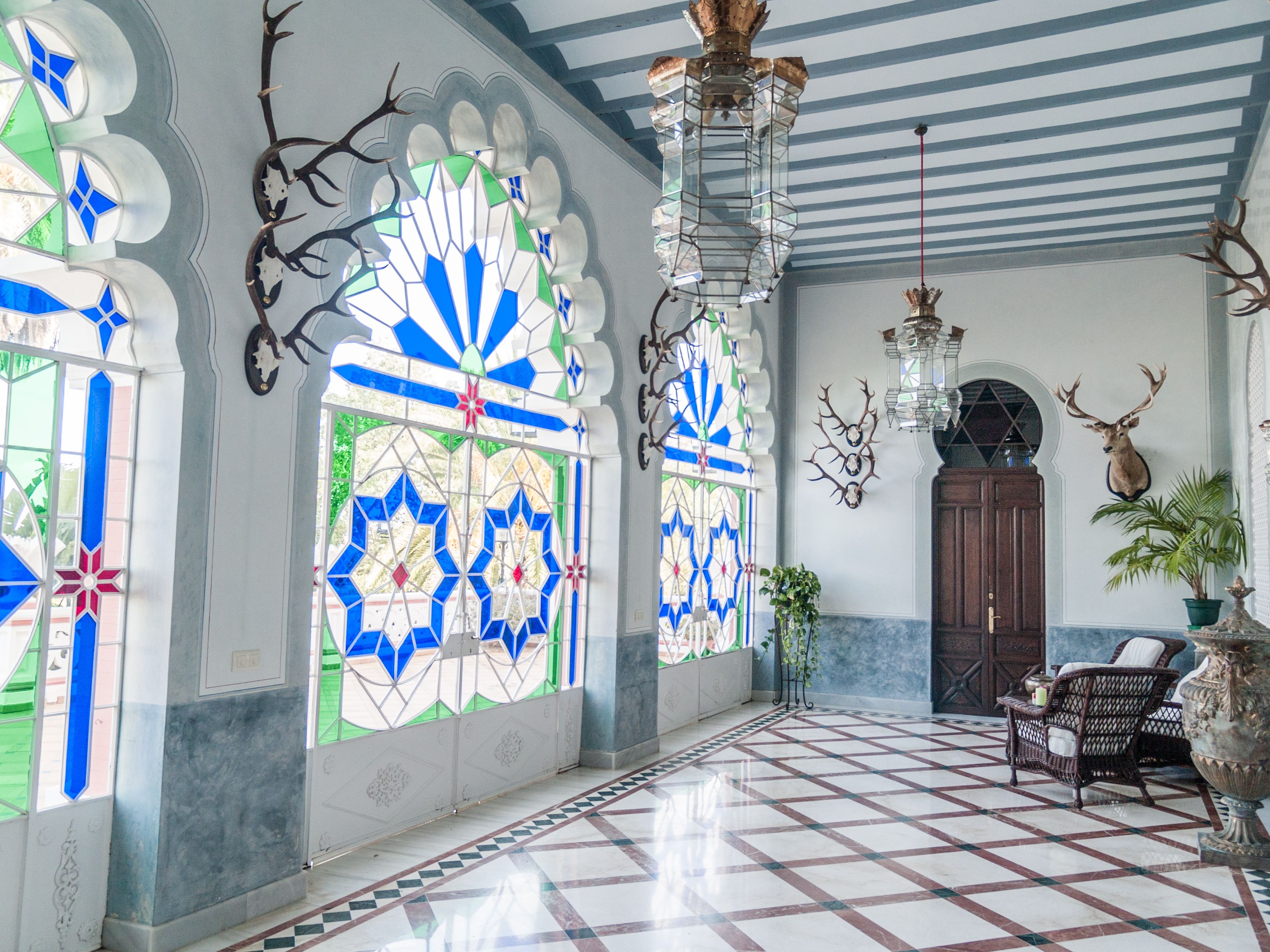 Galería de casa de lujo en Huelva con vidrieras de colores, arcos decorativos y suelo geométrico
