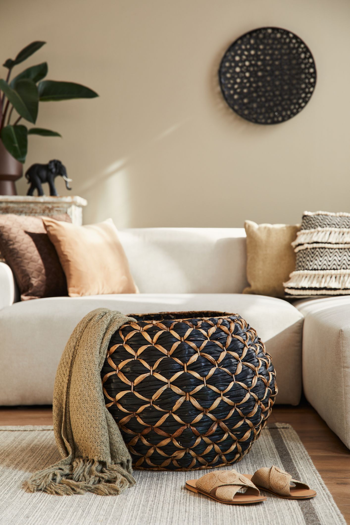 Cesta rígida decorativa usada como mesa auxiliar en el salón junto al sofá con almacenaje interior