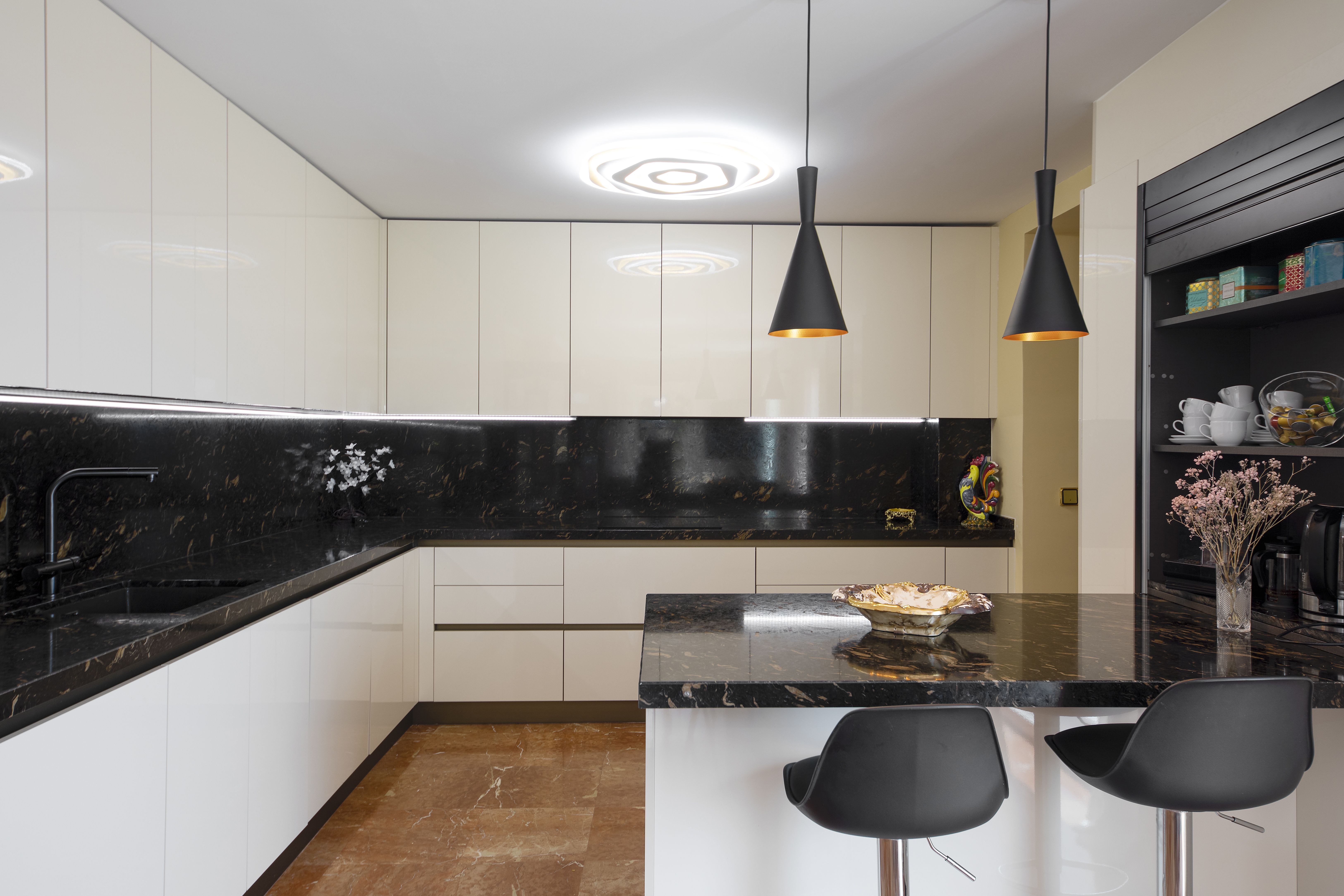 Cocina moderna de chalet de lujo en Málaga con isla central, muebles blancos y encimera negra