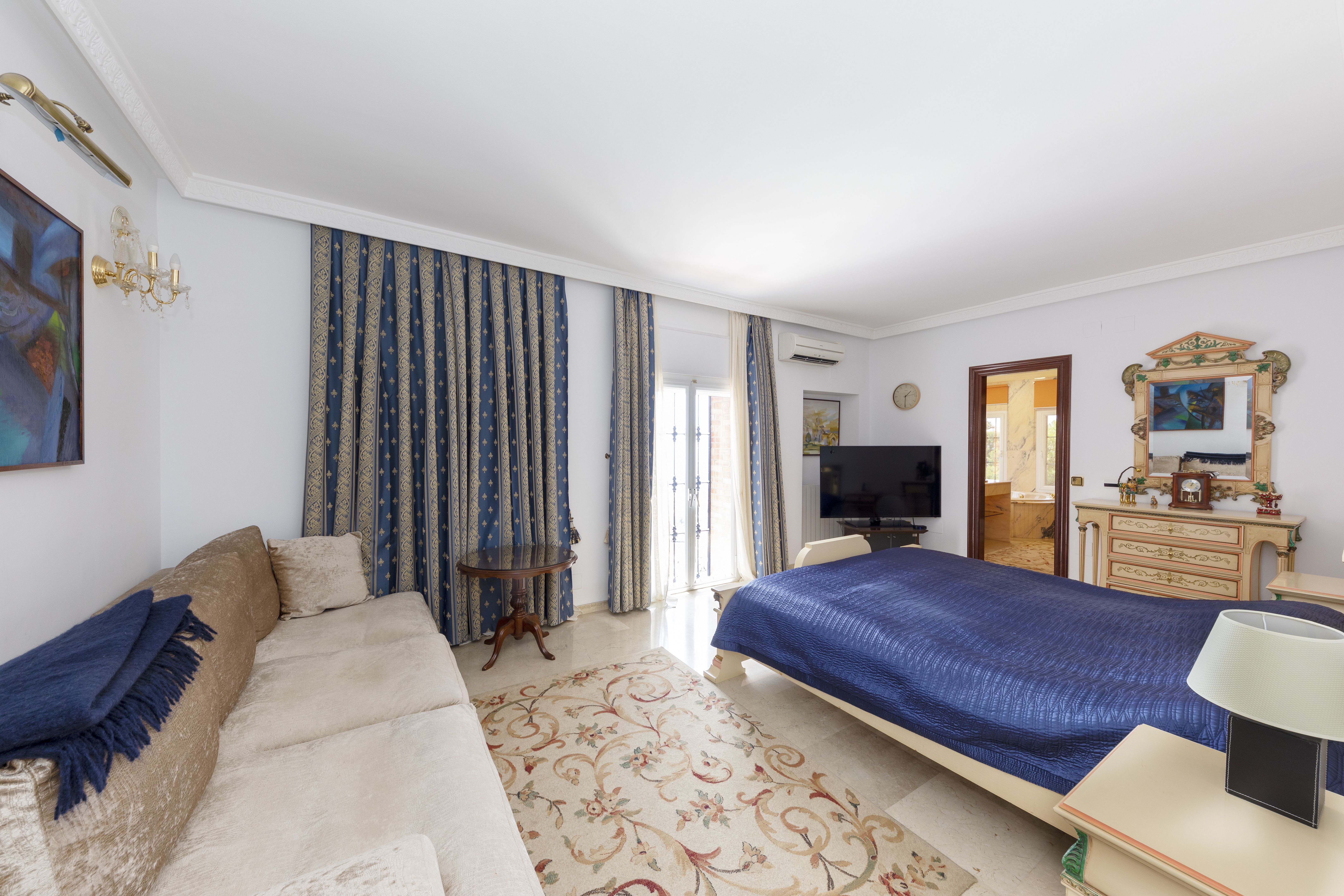 Dormitorio principal de chalet de lujo en Málaga con cama doble, zona de estar y baño en suite