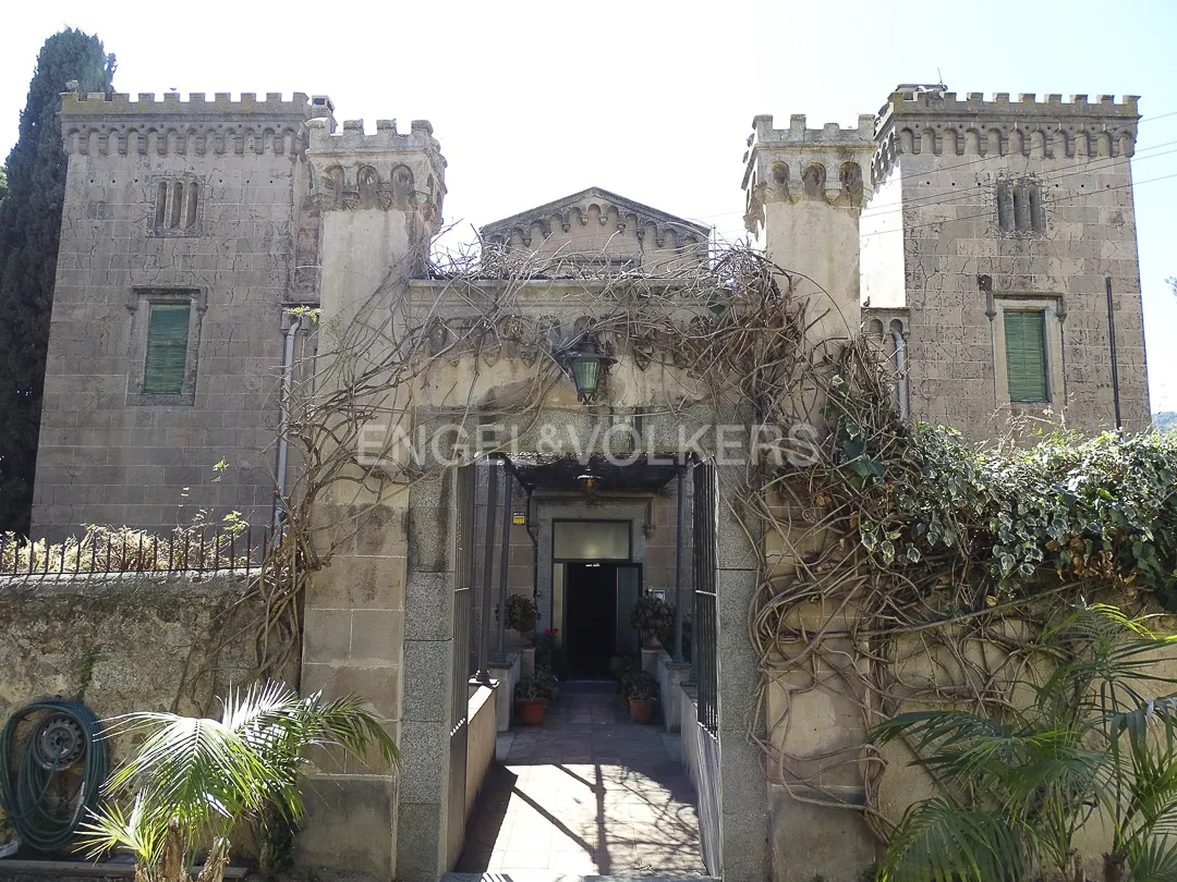 Entrada de casa señorial en Vilassar de Dalt con torres de piedra y acceso ajardinado