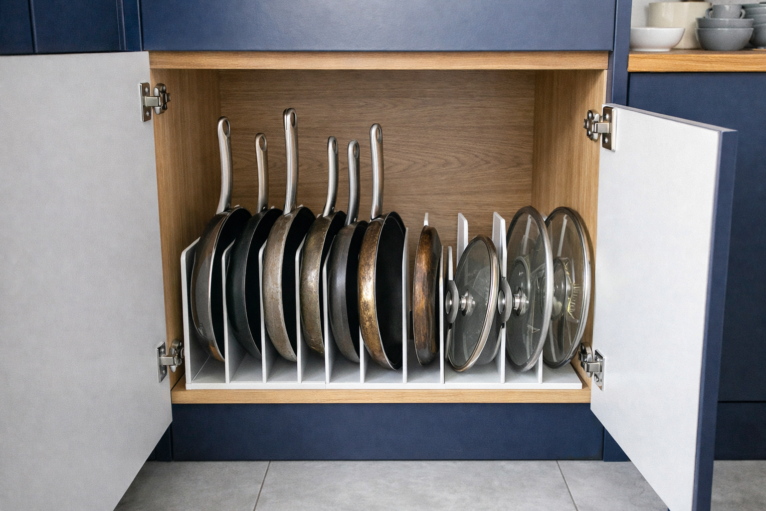 Sartenes y tapas organizadas en vertical dentro de un armario de cocina con separadores para optimizar espacio