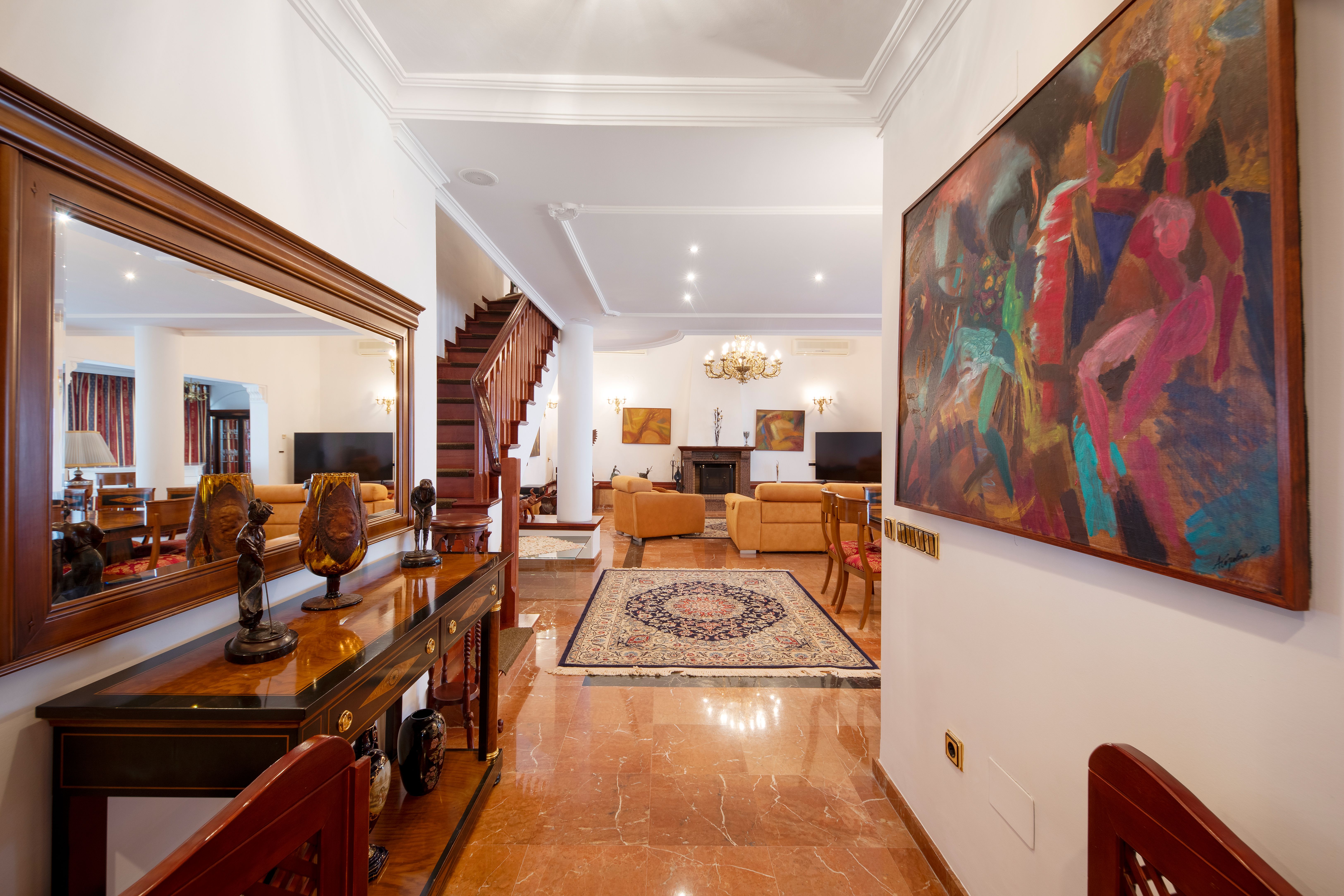 Recibidor de chalet de lujo en Málaga con entrada principal, escalera y salón abierto en Pinares de San Antón