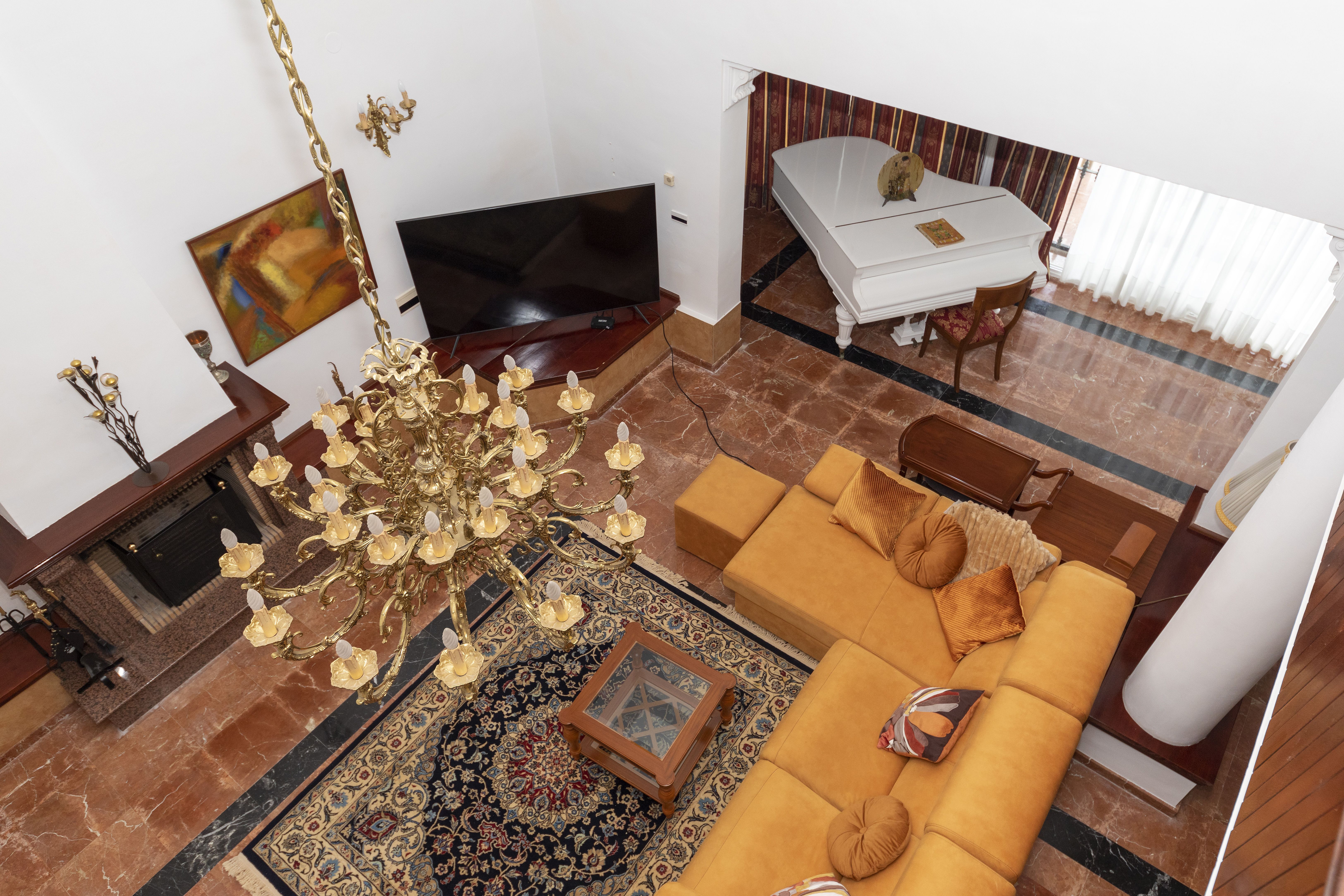 Salón de chalet de lujo en Málaga con chimenea, piano, lámpara clásica y doble altura interior