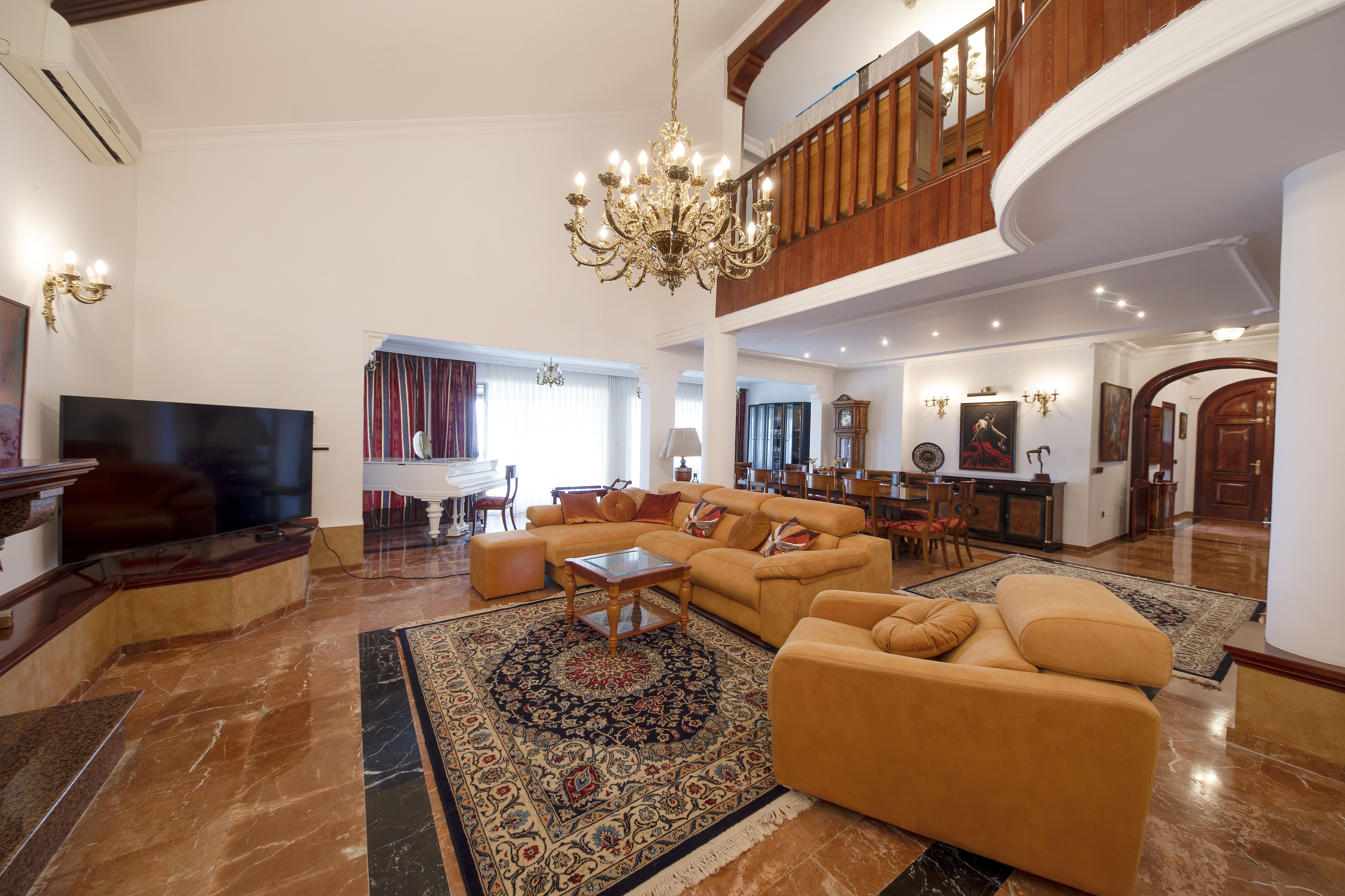 Salón comedor de chalet de lujo en Málaga con doble altura, piano, lámpara clásica y entrada principal