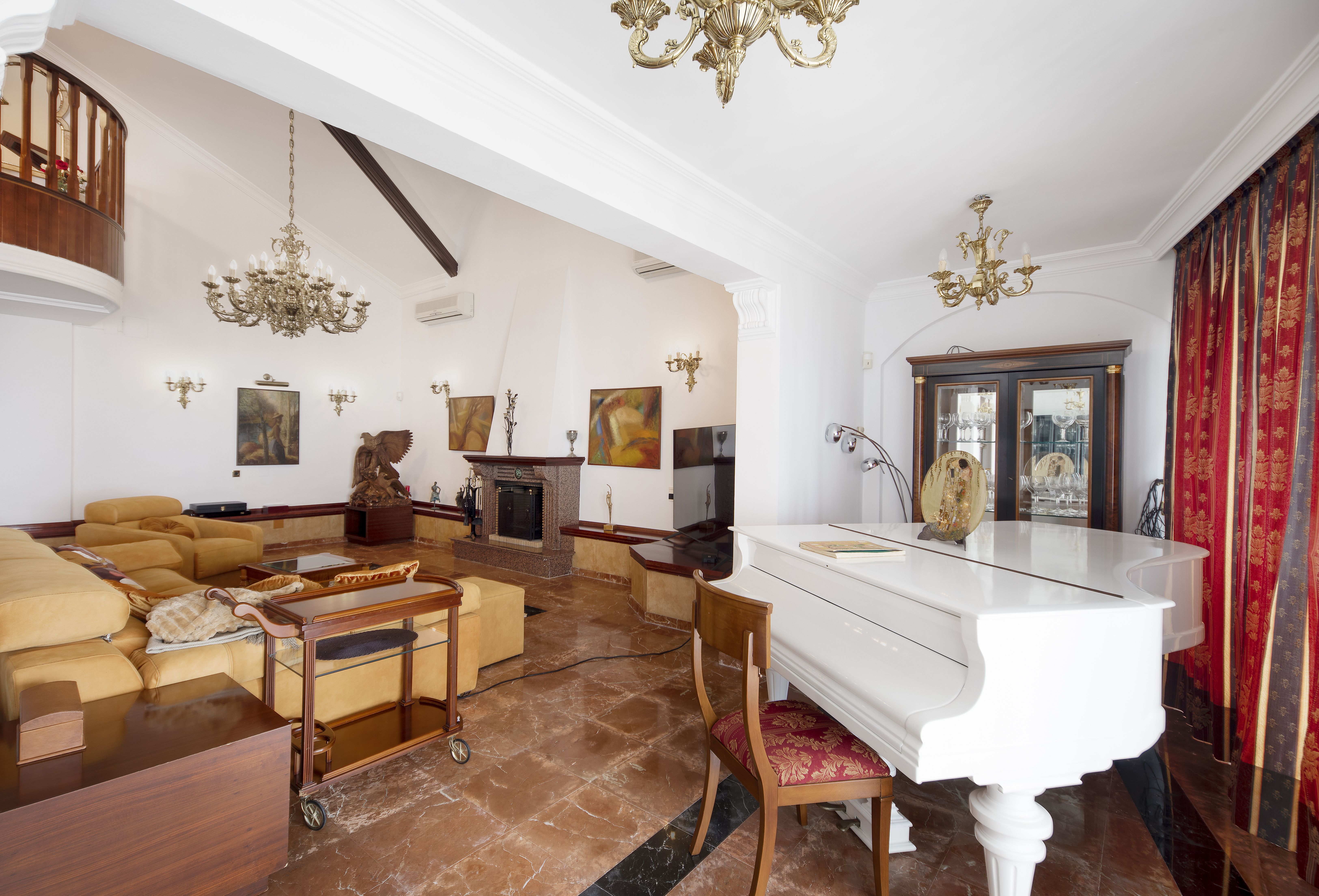Salón principal de chalet de lujo en Málaga con chimenea, piano blanco, techos altos y zona de estar