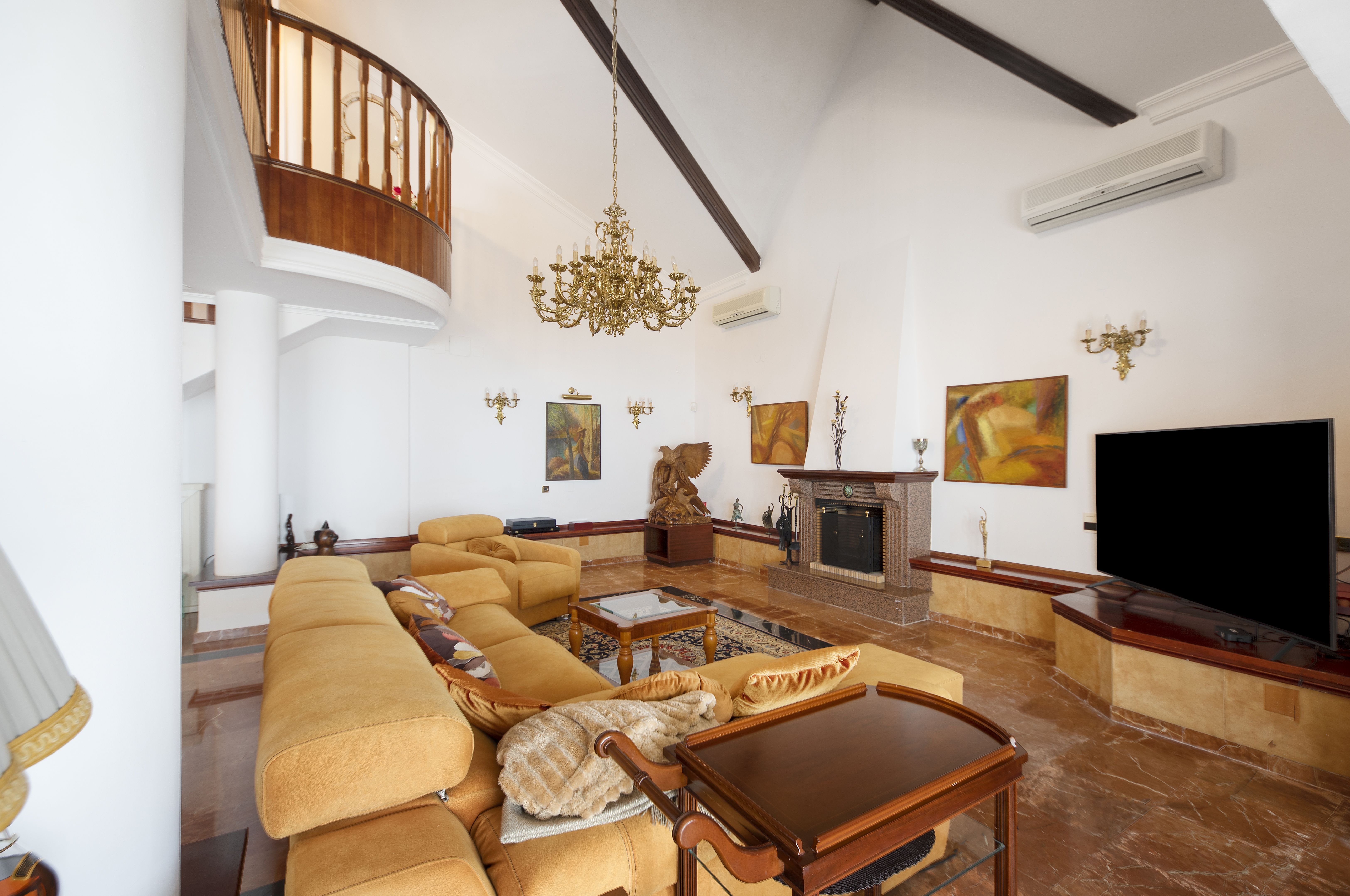 Salón principal de chalet de lujo en Málaga con doble altura, chimenea y grandes ventanales en Pinares de San Antón