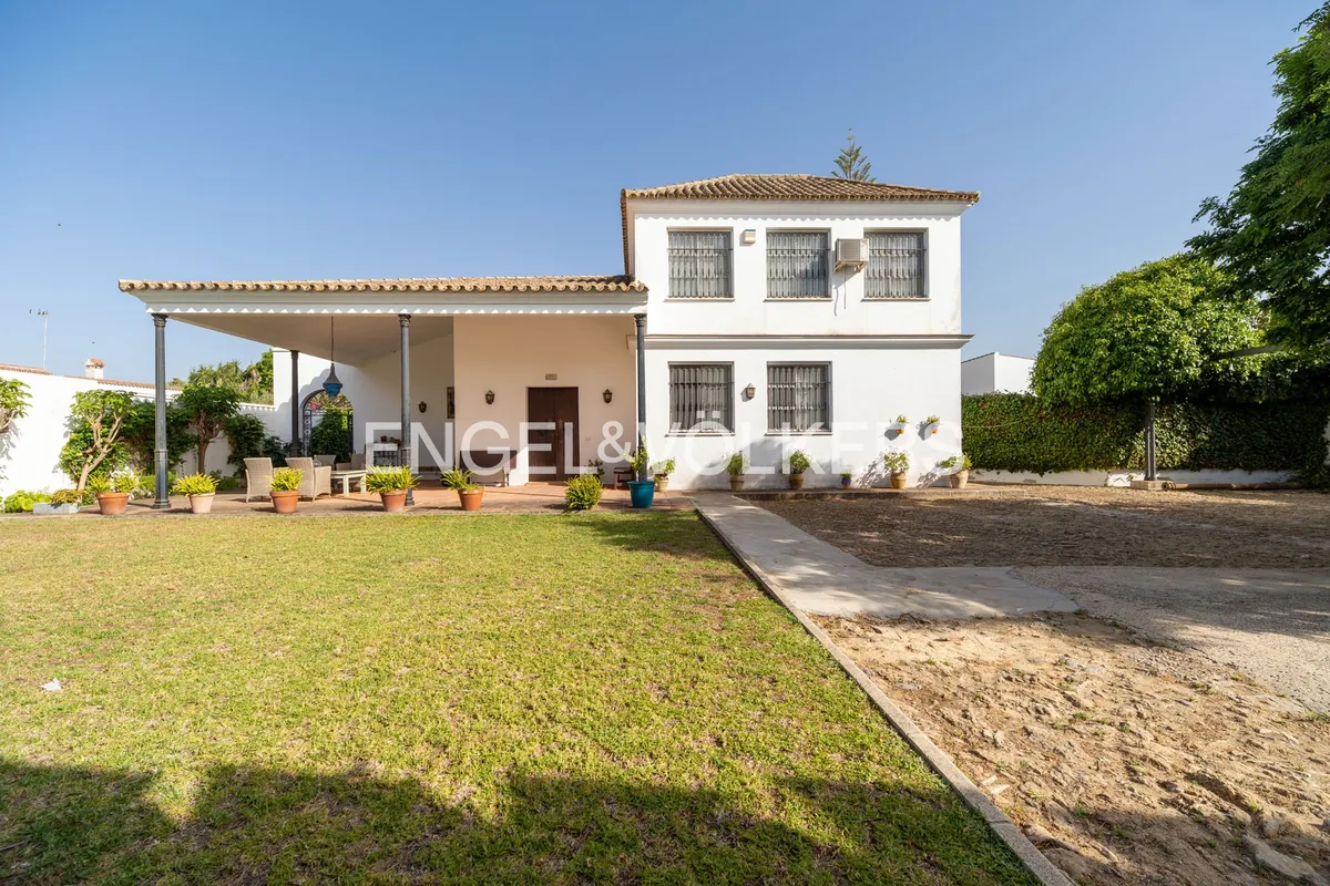 Fachada de casa en la playa de Sanlúcar de Barrameda con jardín, gran porche cubierto y arquitectura andaluza tradicional
