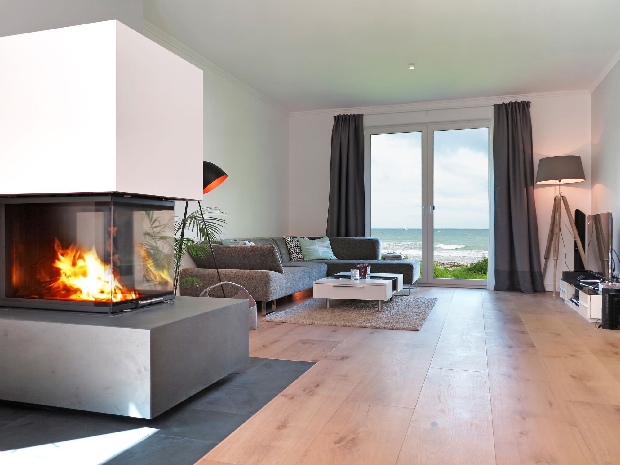 Chimenea decorativa moderna utilizada para separar ambientes en un salón amplio y luminoso