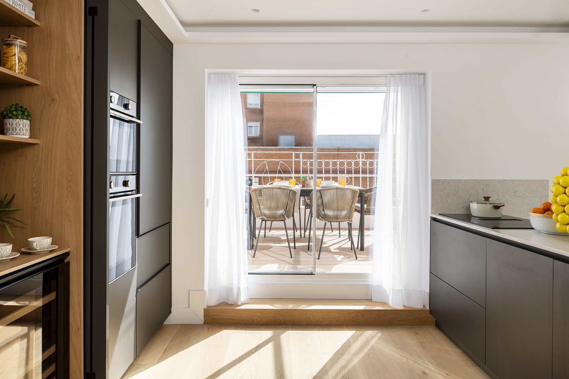 Cocina moderna abierta con acceso directo a una terraza exterior en una vivienda de Chamberí, diseñada para aumentar el valor percibido de una vivienda mediante luz natural y continuidad visual.
