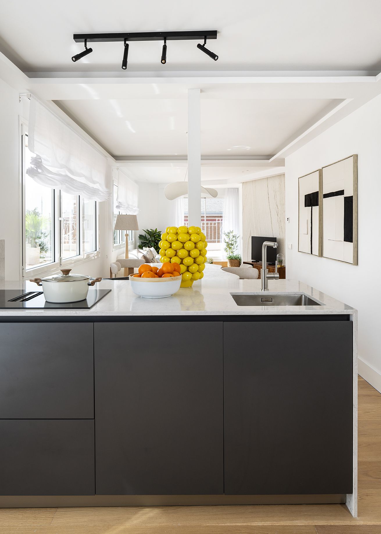 Cocina abierta con isla central, mobiliario oscuro y encimera clara integrada en la zona de día de una vivienda de Chamberí, diseñada para aumentar el valor percibido de una vivienda.
