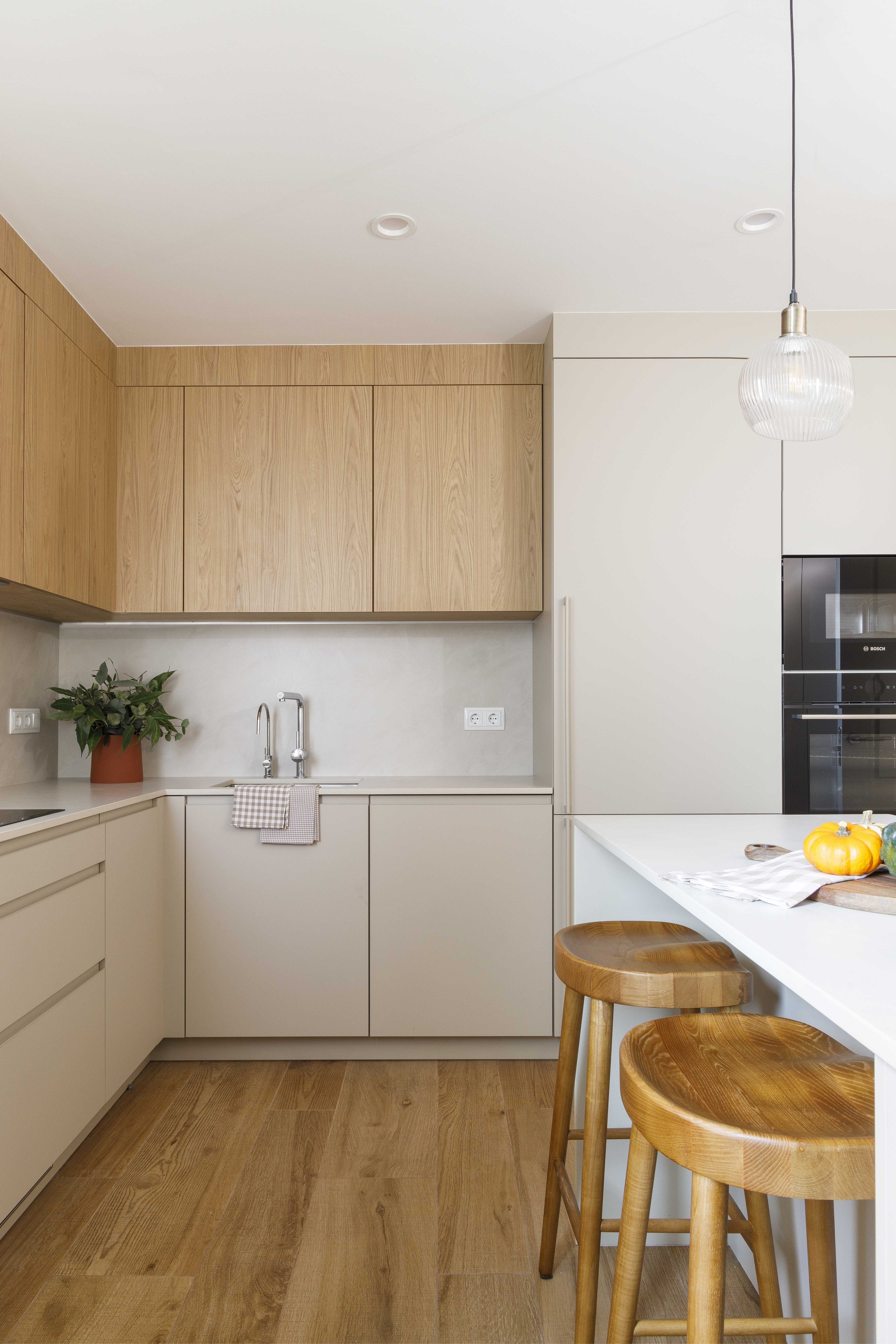 Cocina pequeña reformada con barra y muebles en tonos beige y madera natural