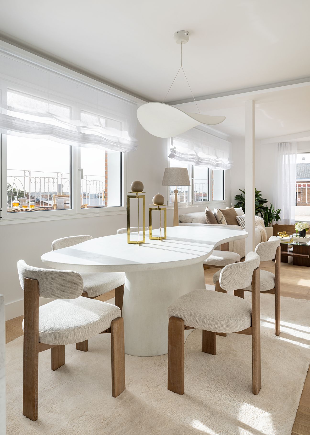Comedor luminoso con mesa de diseño orgánico, sillas tapizadas y grandes ventanales en una vivienda de Chamberí, concebido para aumentar el valor percibido de una vivienda.