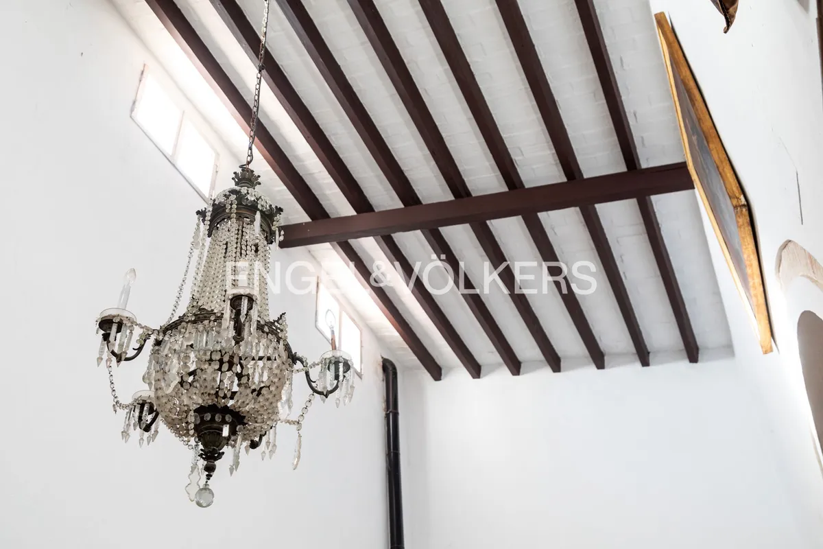 Detalle de techos altos con vigas de madera y lámpara de araña en casa andaluza tradicional
