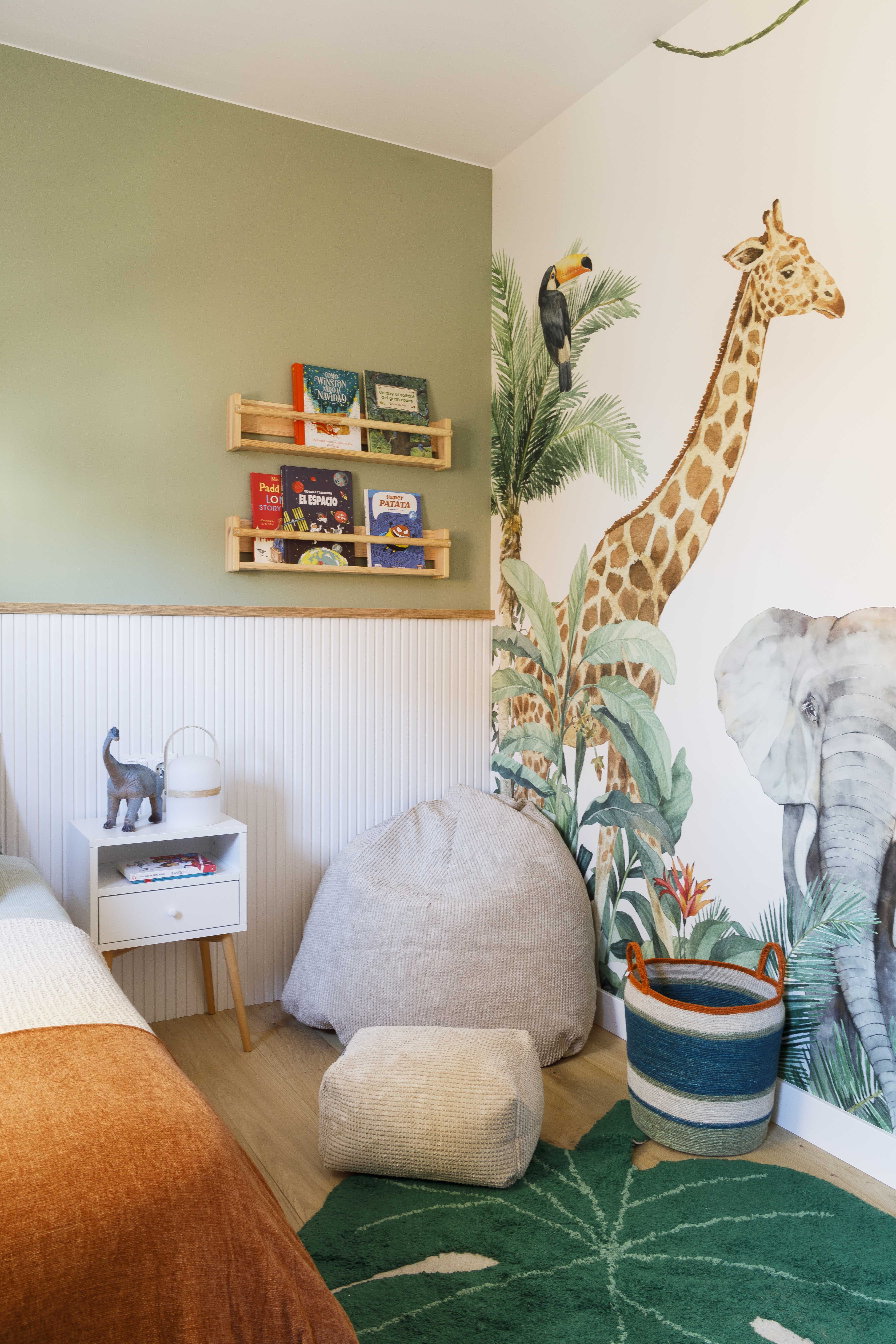 Dormitorio infantil con mural de animales de la selva y rincón de juegos en una vivienda reformada