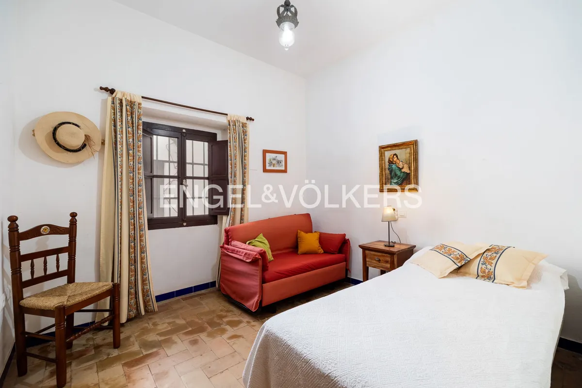 Dormitorio secundario con sofá y ventana de madera en casa andaluza en Sanlúcar de Barrameda