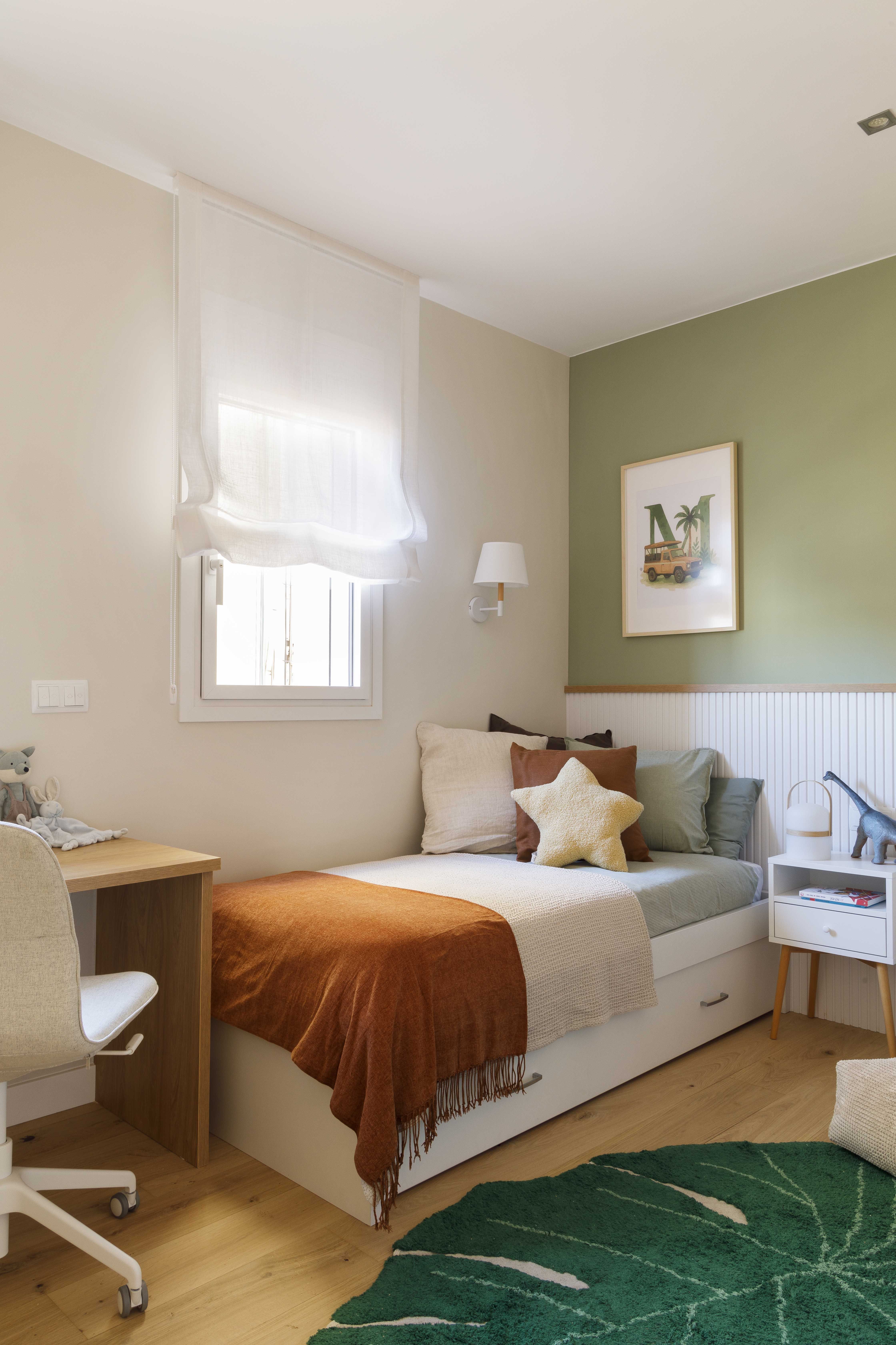 Habitación infantil de niño con pared verde, librerías de madera y zona de juegos