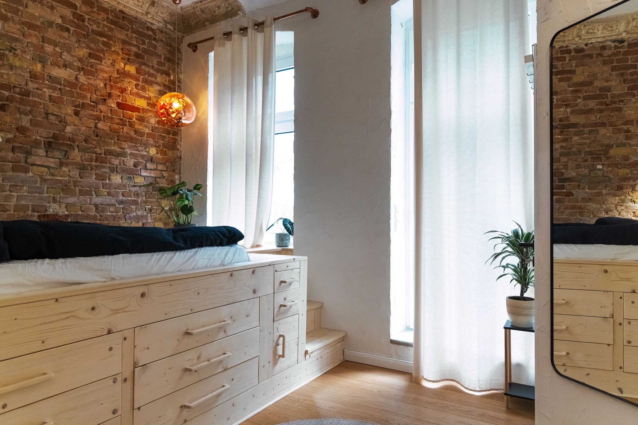 Dormitorio con plataforma elevada y almacenaje oculto para separar ambientes en un loft moderno