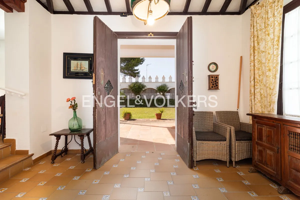 Recibidor abierto al jardín en casa en la playa de Sanlúcar de Barrameda con puertas de madera originales