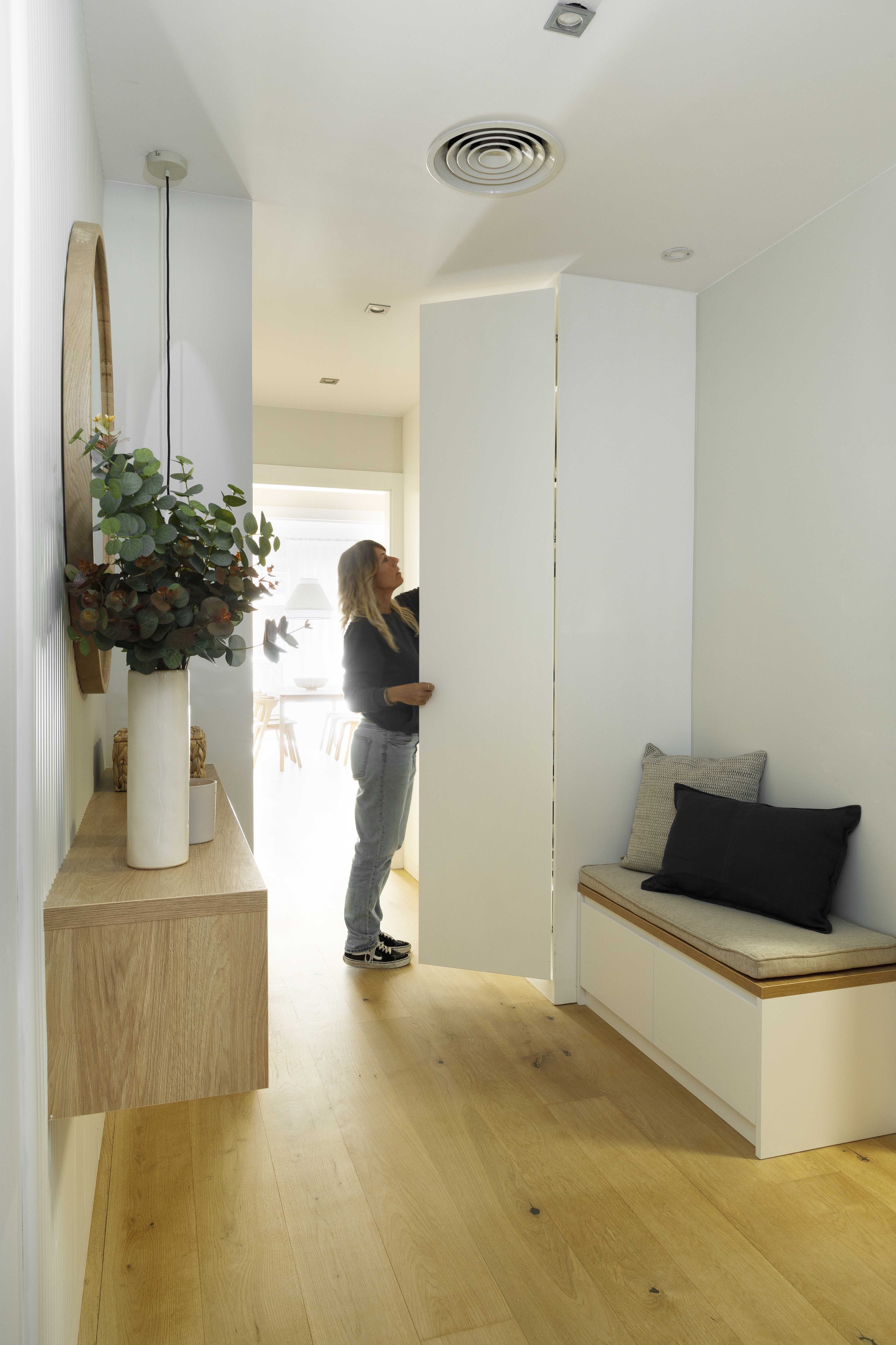 Recibidor funcional con banco de almacenaje y mueble suspendido en una vivienda familiar reformada