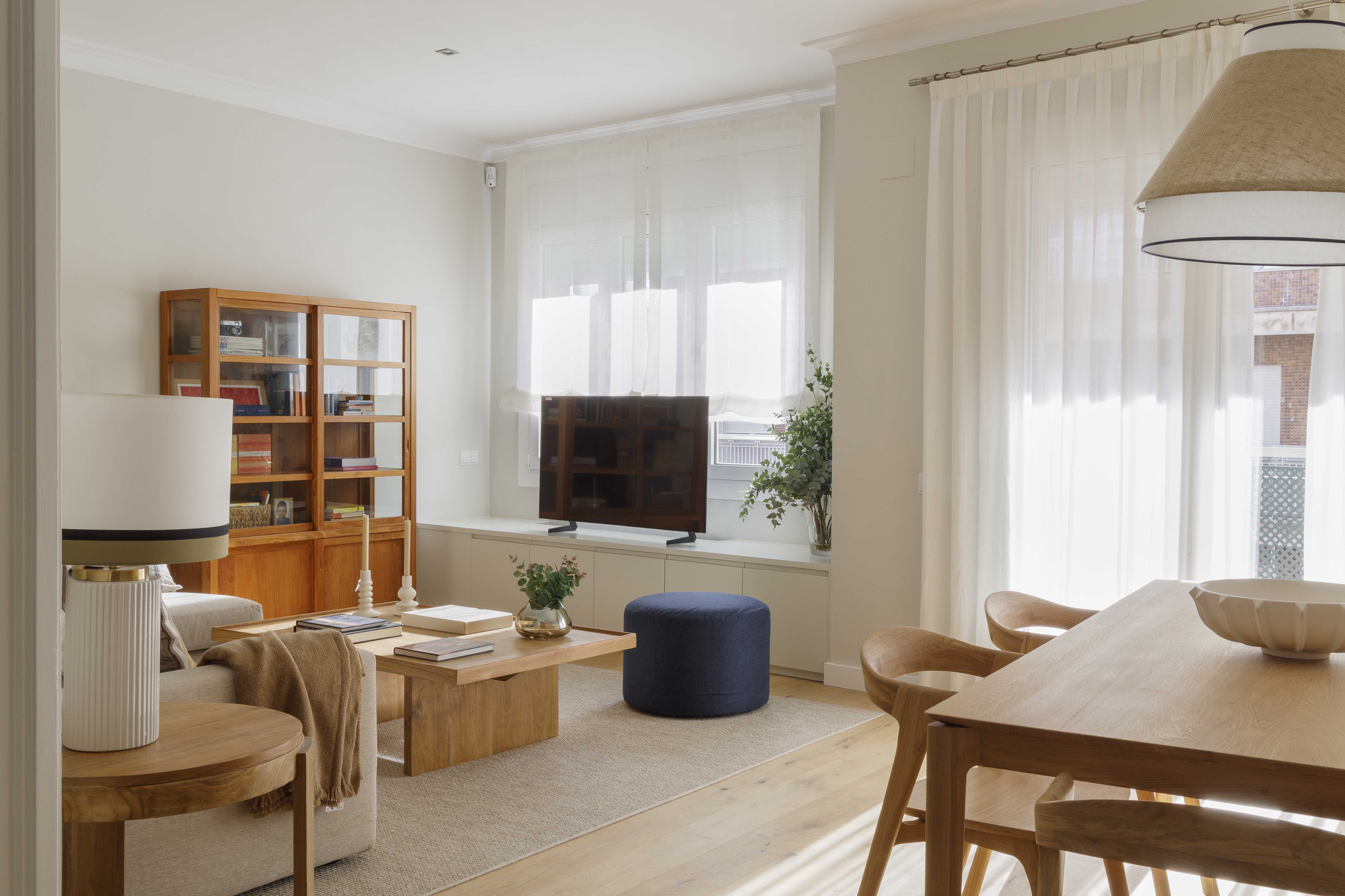 Detalle de salón reformado con sofá beige, muebles de madera y decoración cálida en una vivienda familiar