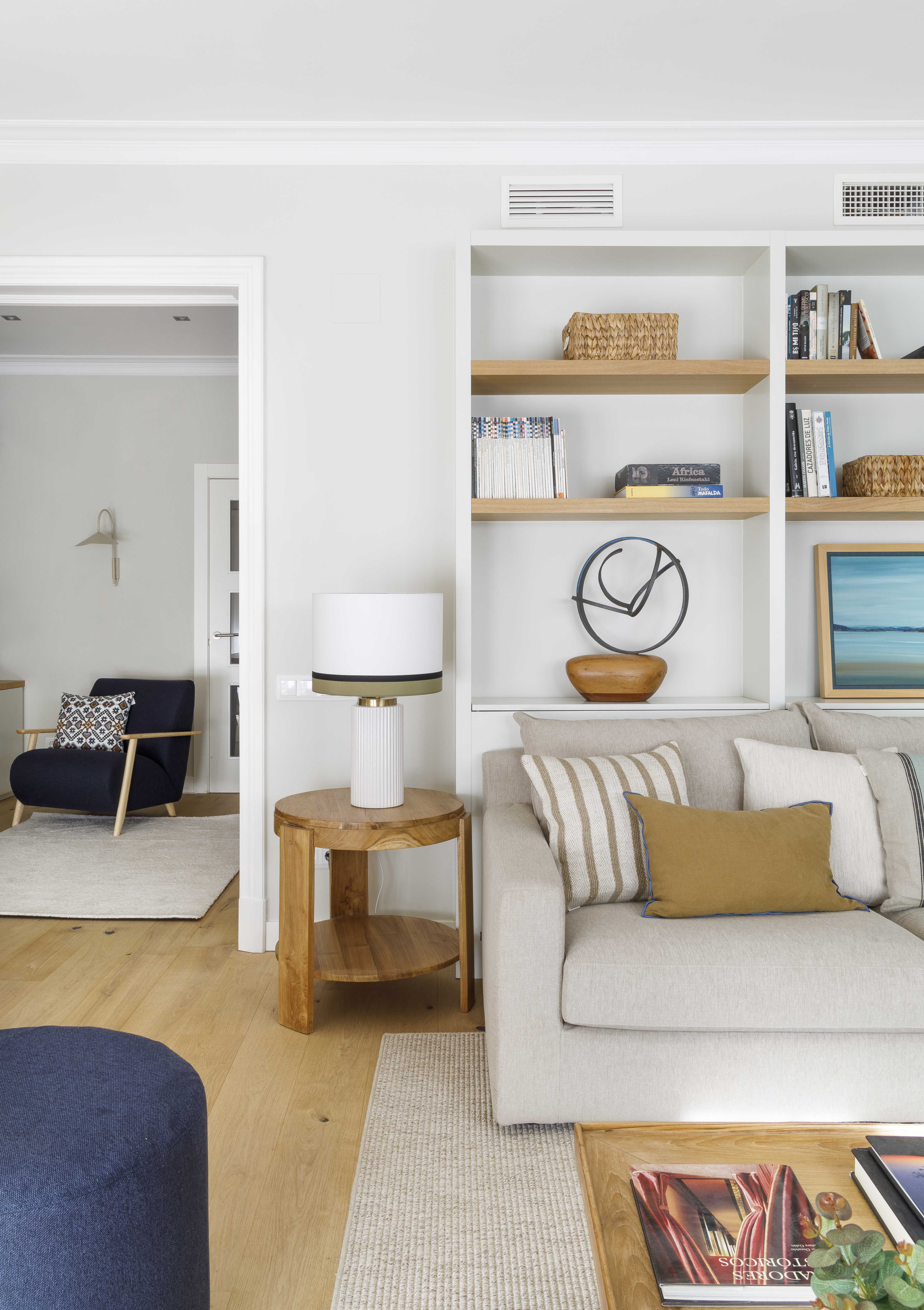 Salón reformado con estantería a medida y sofá en tonos neutros en una vivienda familiar luminosa
