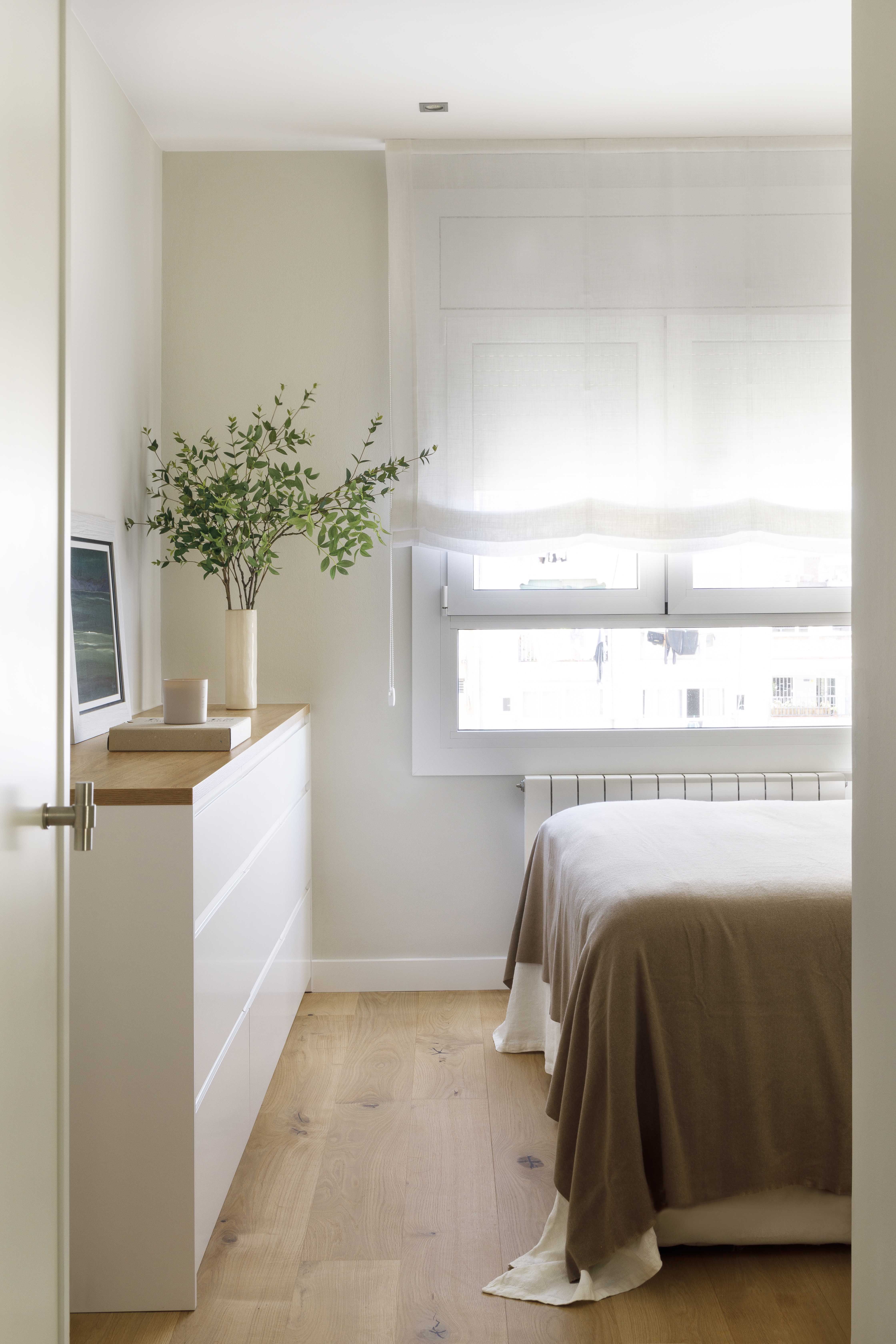 Suite principal luminosa con cómoda blanca, suelo de roble y textiles neutros en una vivienda reformada