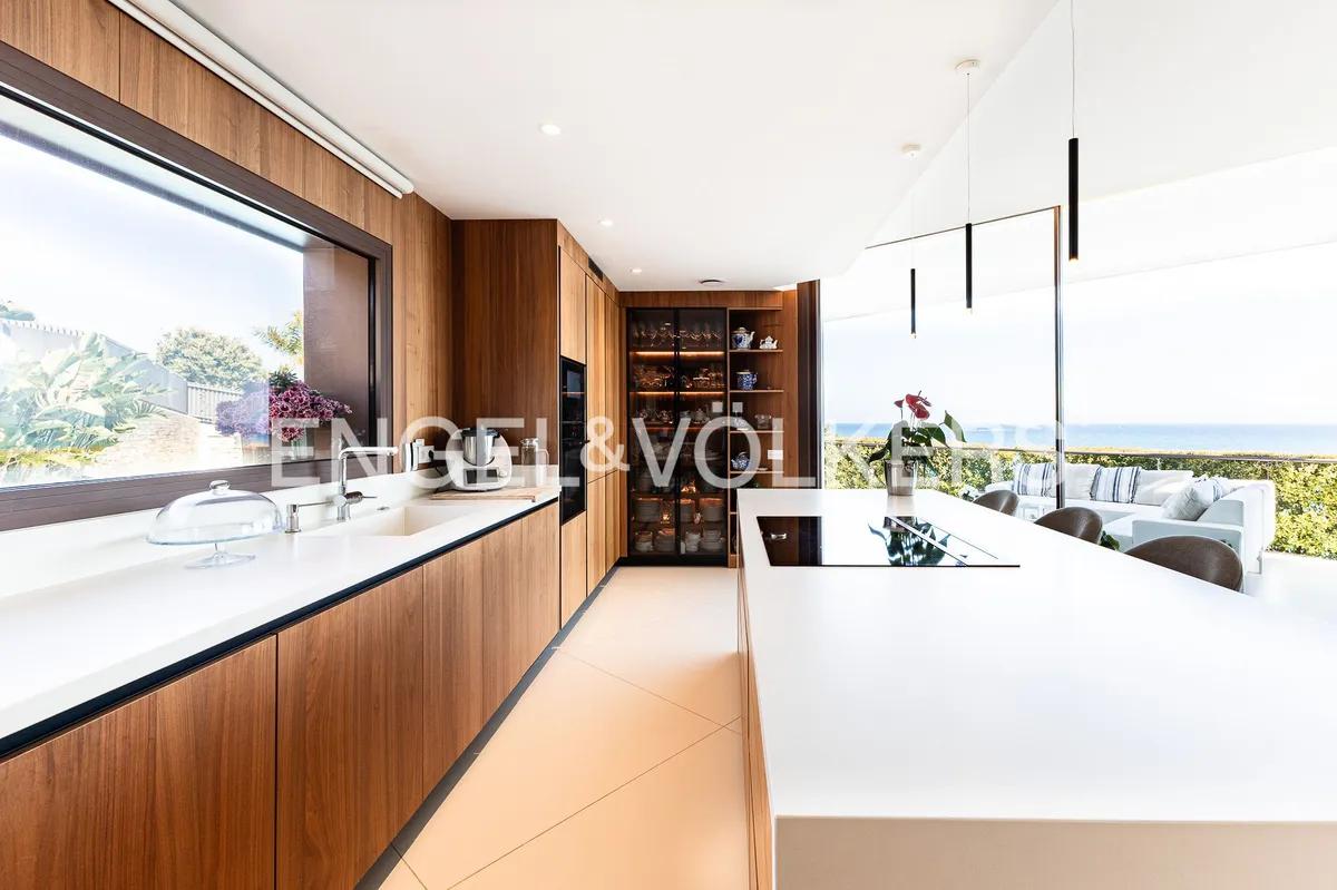 Cocina abierta con isla central, mobiliario de madera y diseño contemporáneo en una casa de Sant Pol de Mar.