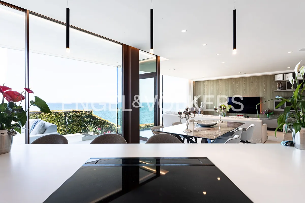 Cocina abierta y comedor de una casa en Sant Pol de Mar con grandes ventanales y vistas al Mediterráneo.
