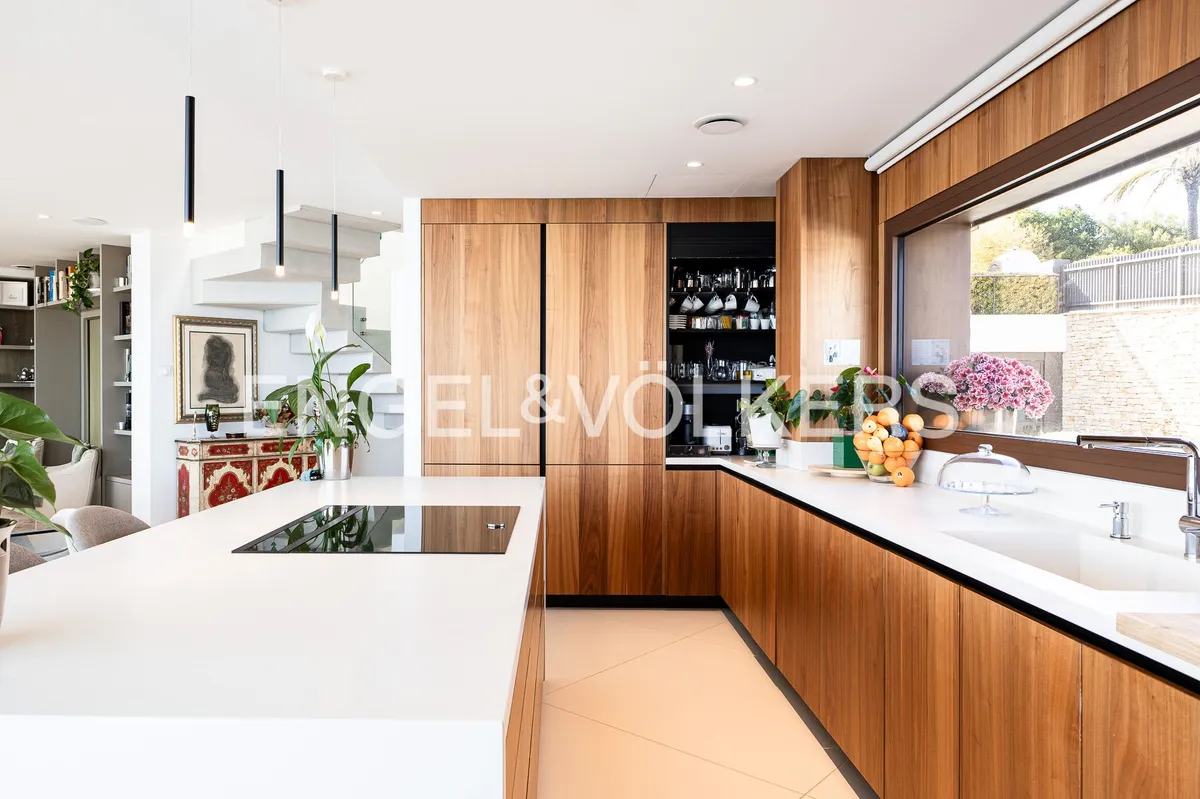 Cocina de una casa en Sant Pol de Mar con isla central, taburetes y mobiliario de madera natural.