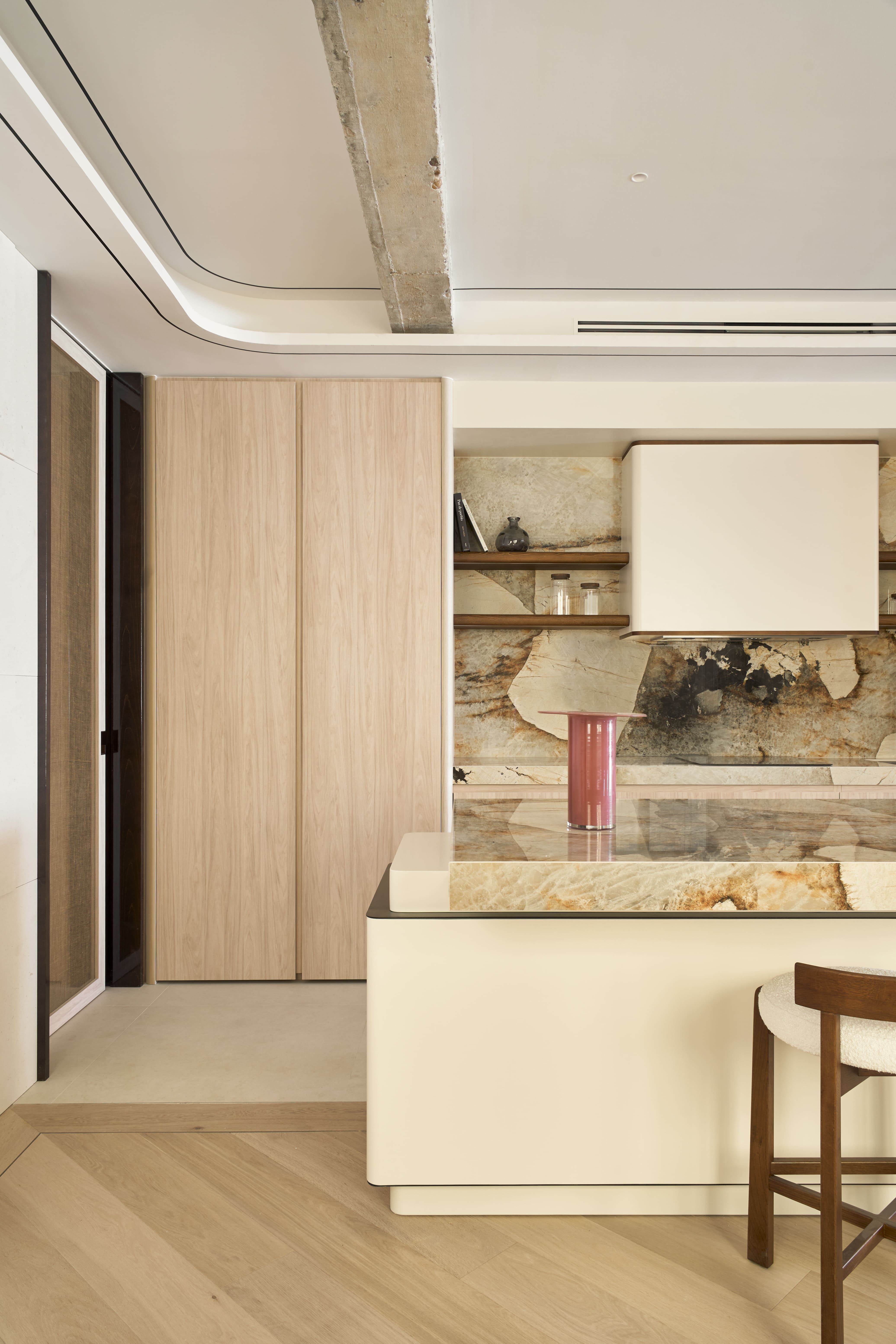Cocina abierta con isla revestida en mármol Patagonia y mobiliario panelado, un recurso para crear un punto focal en una casa elegante.