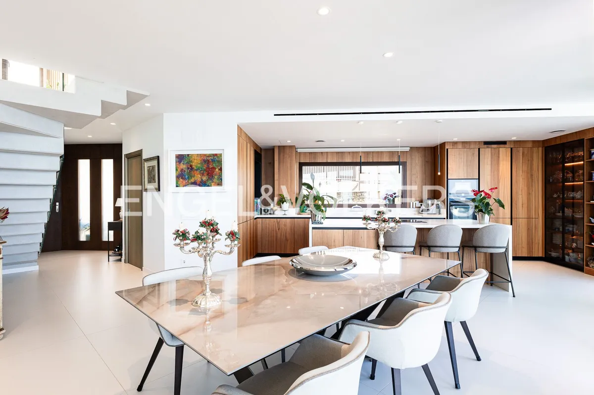 Comedor y cocina abierta de una casa en Sant Pol de Mar con diseño contemporáneo, isla central y acabados en madera natural.