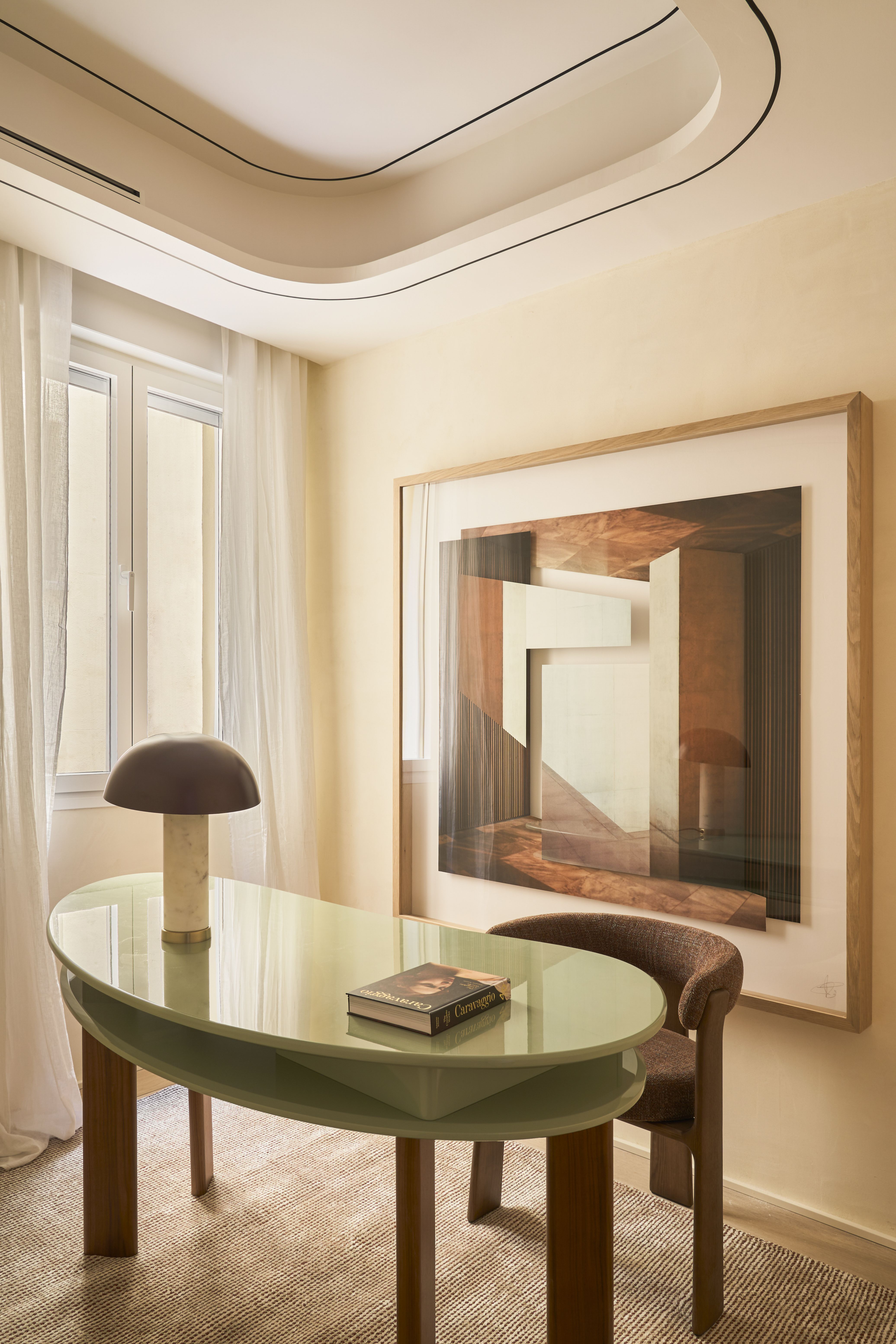 Despacho de diseño con mesa ovalada, obra de arte de gran formato y líneas curvas en una vivienda contemporánea.