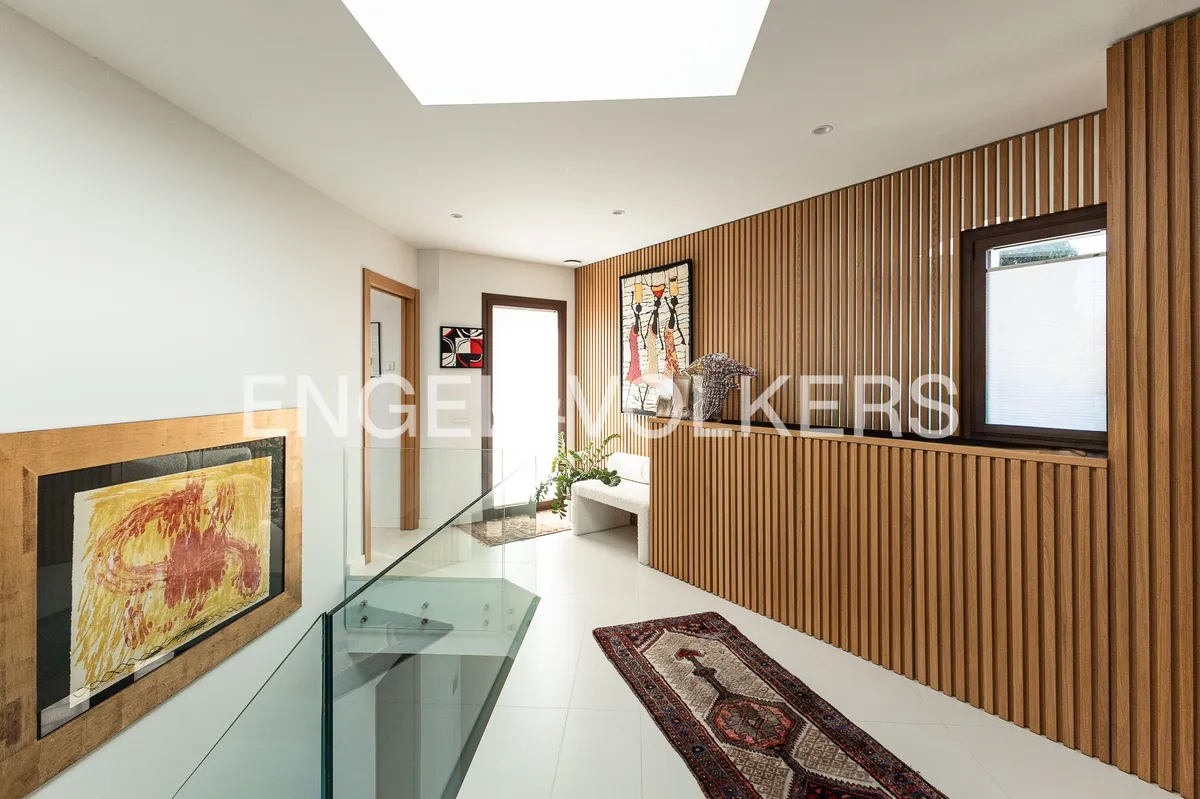 Distribuidor de una casa en Sant Pol de Mar con revestimiento de madera, claraboya y diseño contemporáneo.