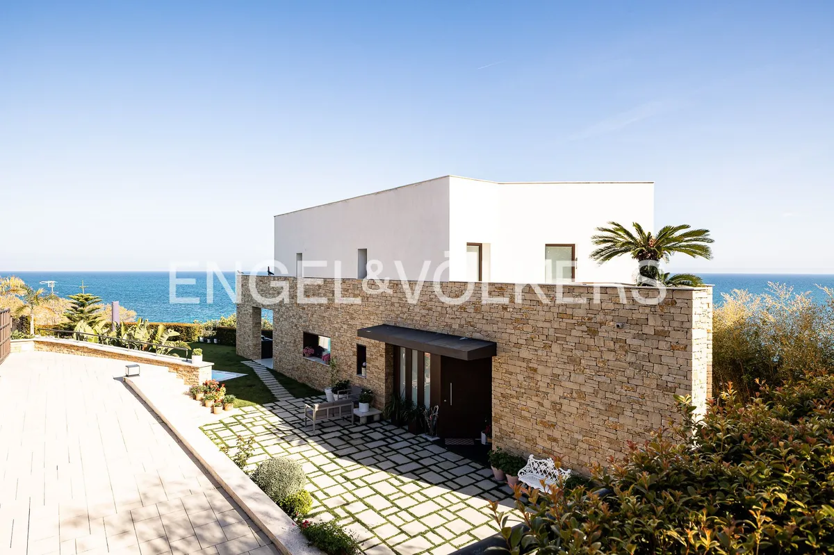 Fachada de una casa en Sant Pol de Mar con revestimiento de piedra natural, arquitectura contemporánea y vistas al Mediterráneo.