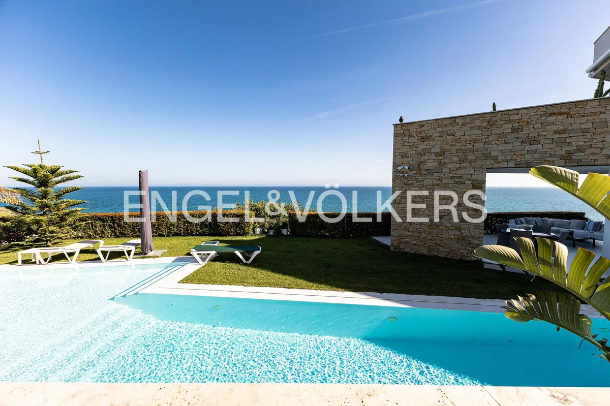 Piscina climatizada con vistas al Mediterráneo en una casa de Sant Pol de Mar con jardín y arquitectura contemporánea.